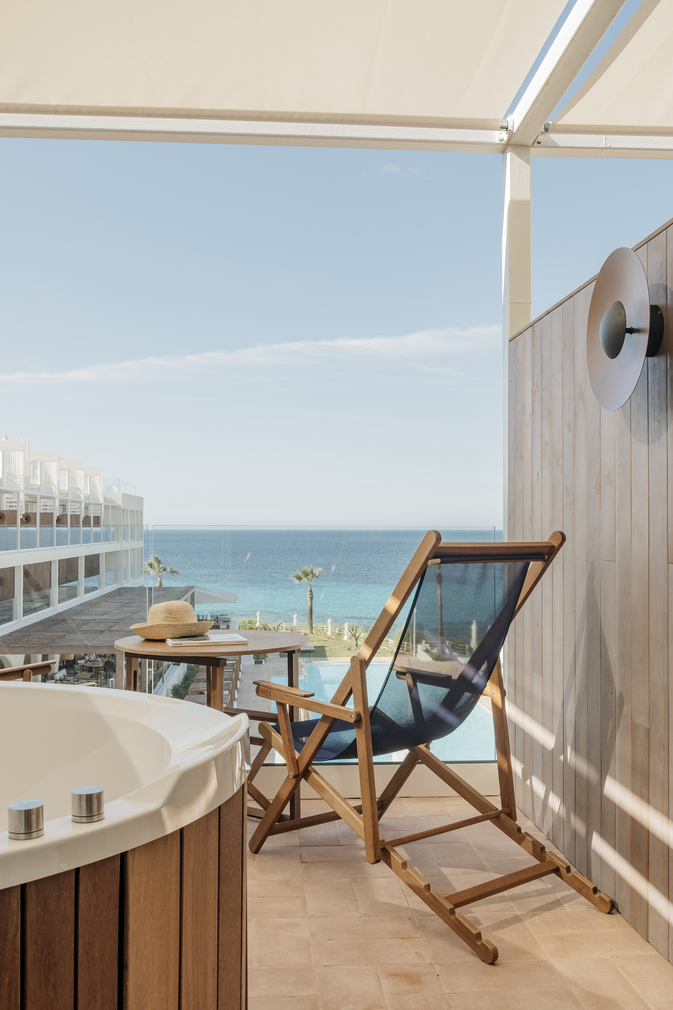 Hotel balcony with sea view, private hot tub, and lounge chair.