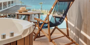 a chair and a bathtub on a balcony overlooking the ocean
