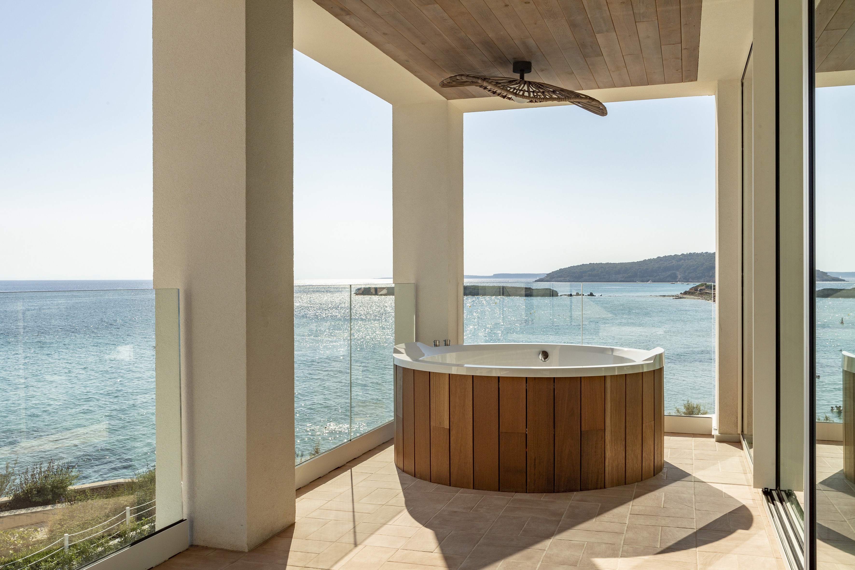Oceanfront balcony with wooden hot tub and panoramic sea views.