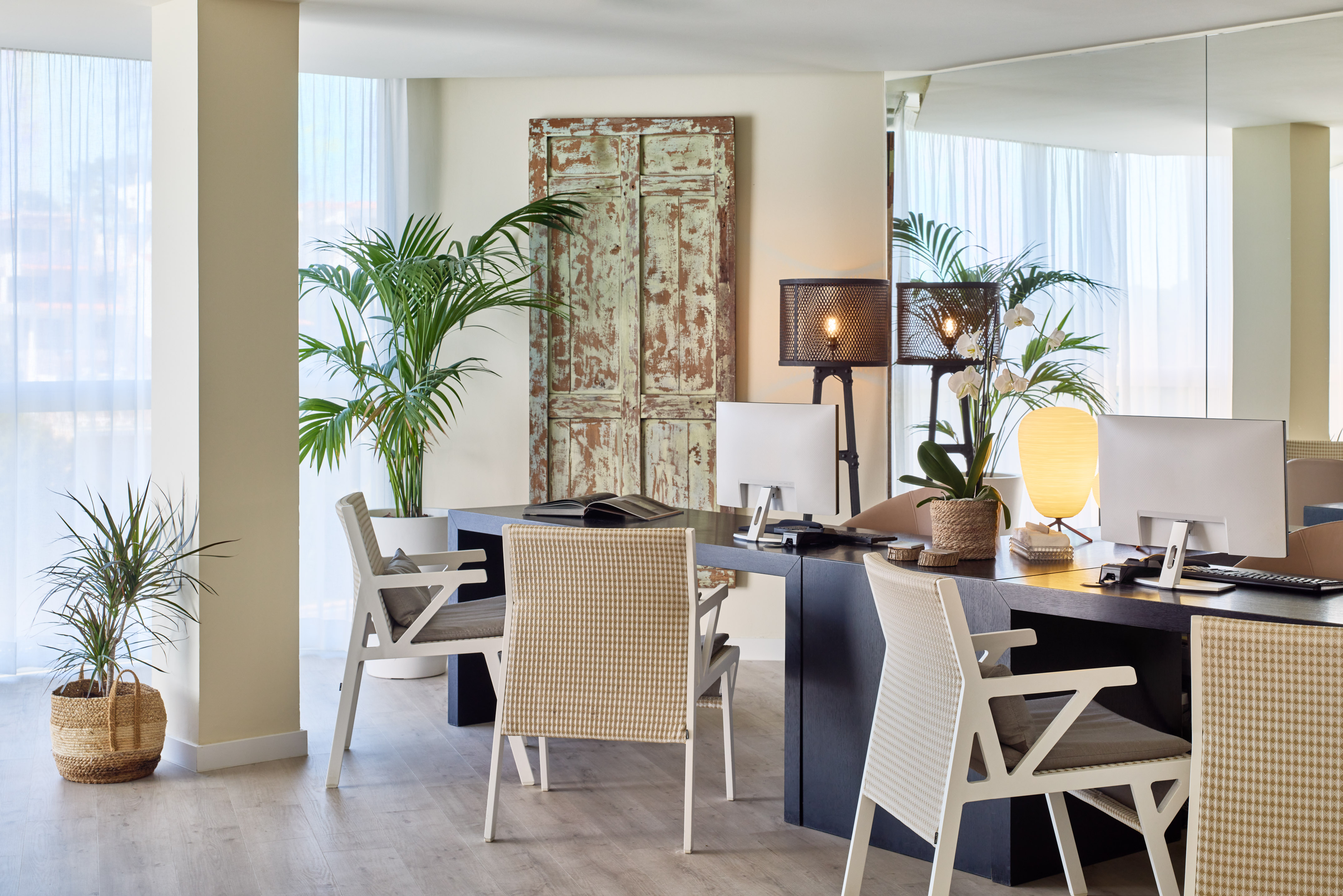Modern reception with dual workstations, stylish chairs, and lush green plants.