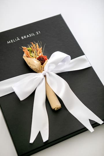 a black box with a white ribbon and a bouquet of flowers