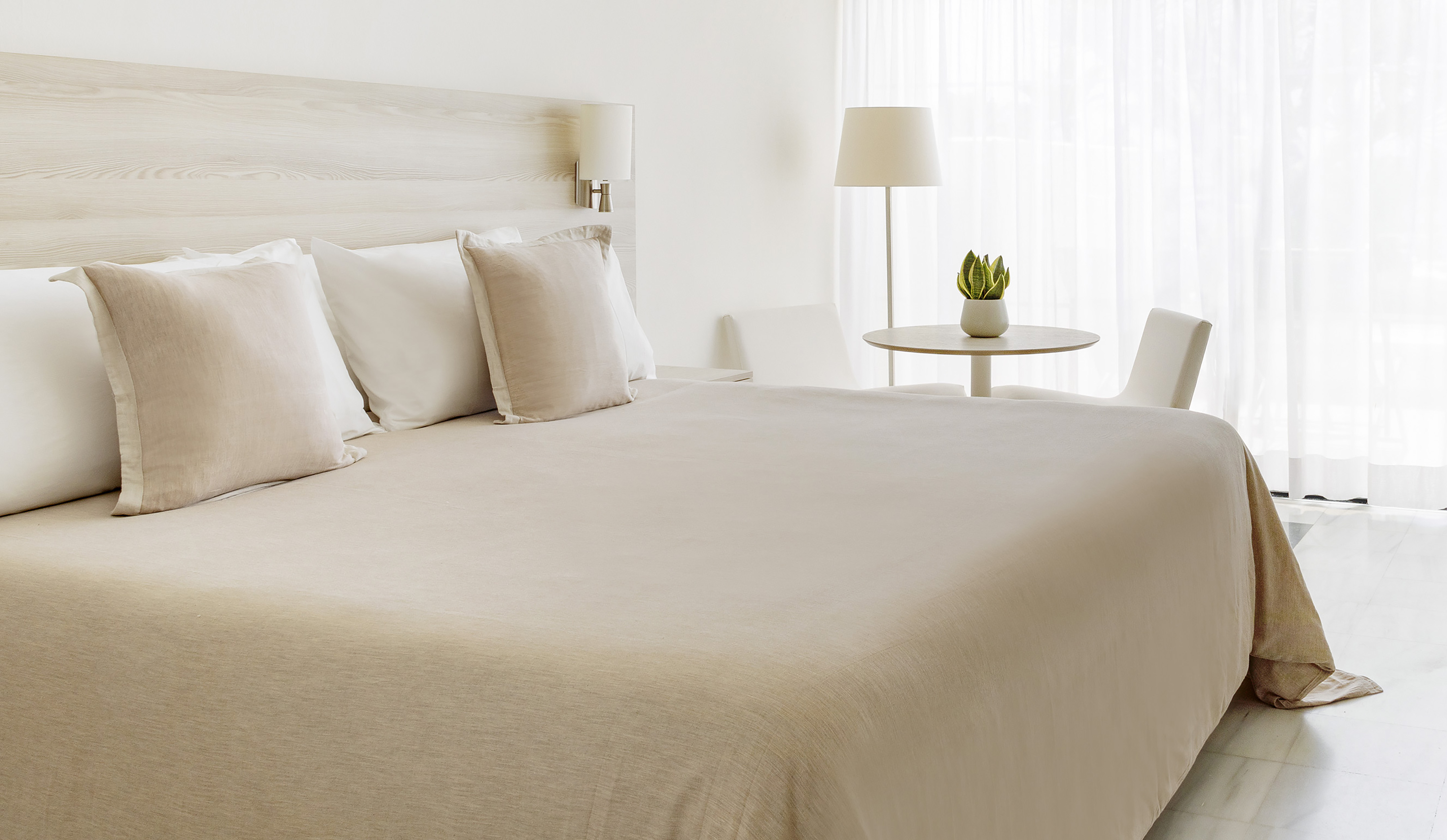 Modern neutral bedroom with beige bed, wood headboard, and soft light.