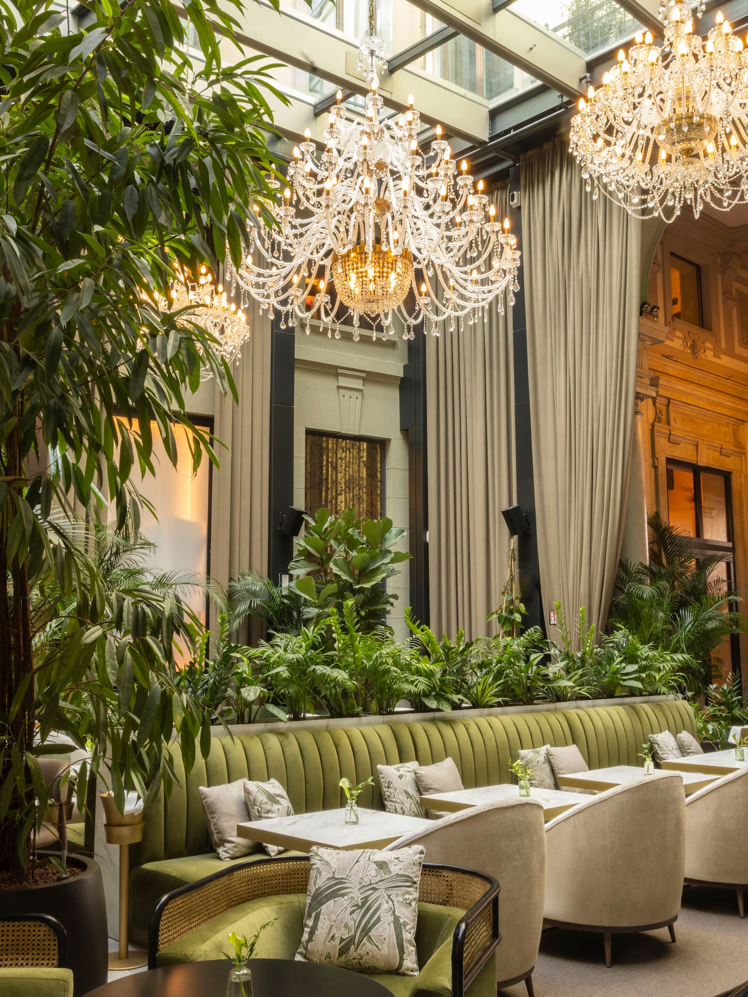 Chic restaurant atrium with lush plants, sparkling chandeliers, and stylish seating.