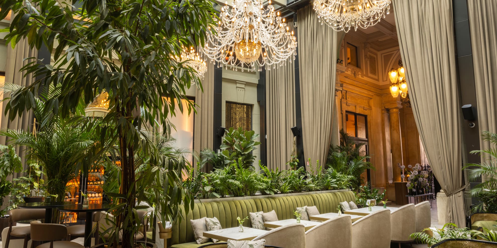 a room with a large chandelier and tables and chairs