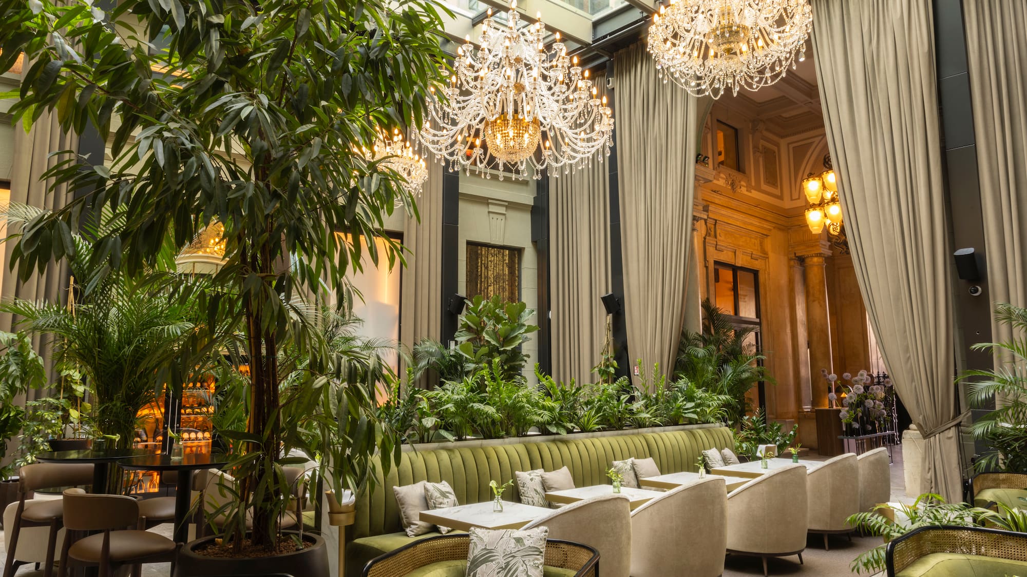 a room with a large chandelier and tables and chairs