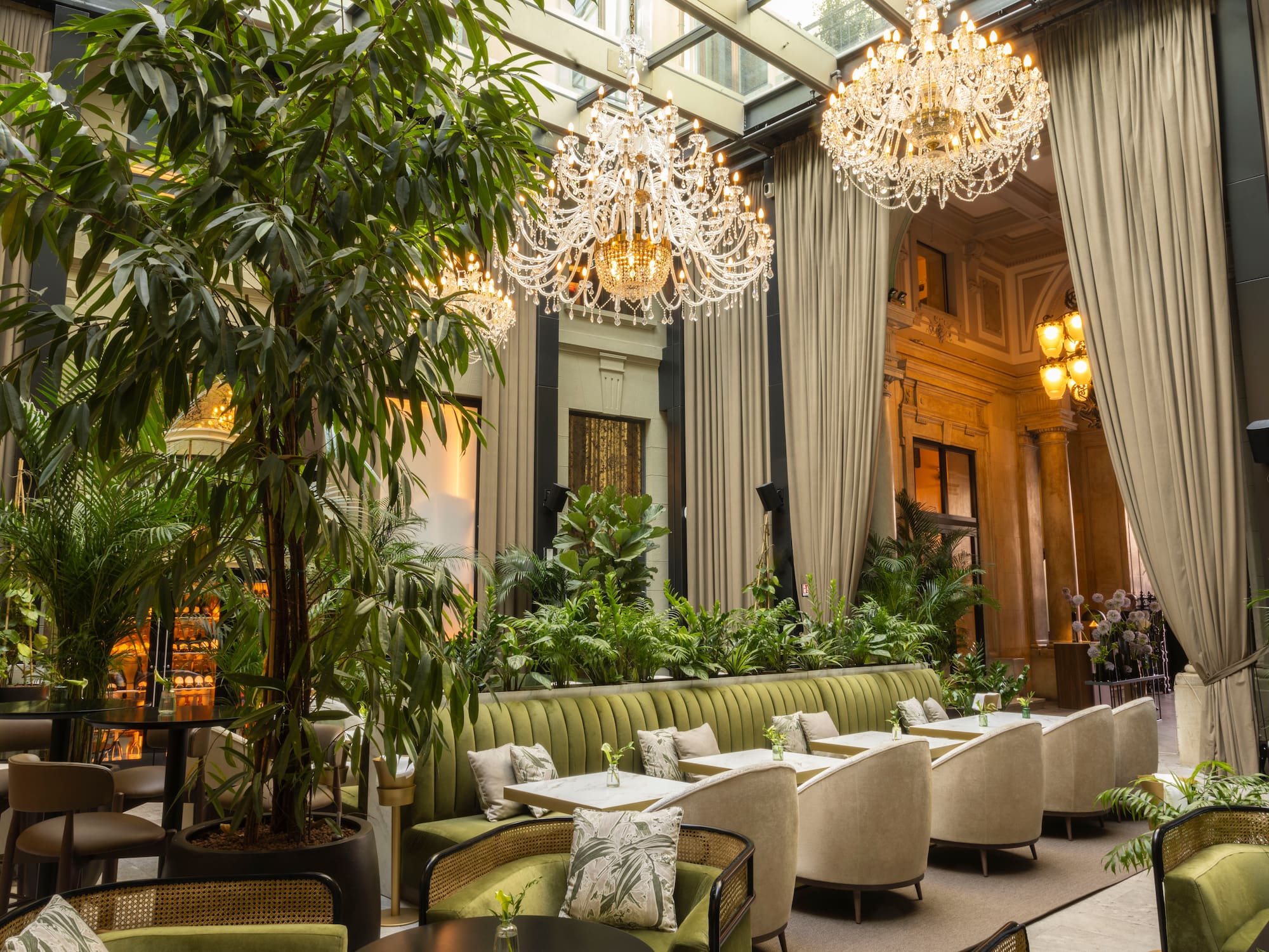 Lush green restaurant interior with crystal chandeliers and elegant seating.