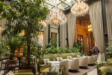 a room with a large chandelier and tables and chairs