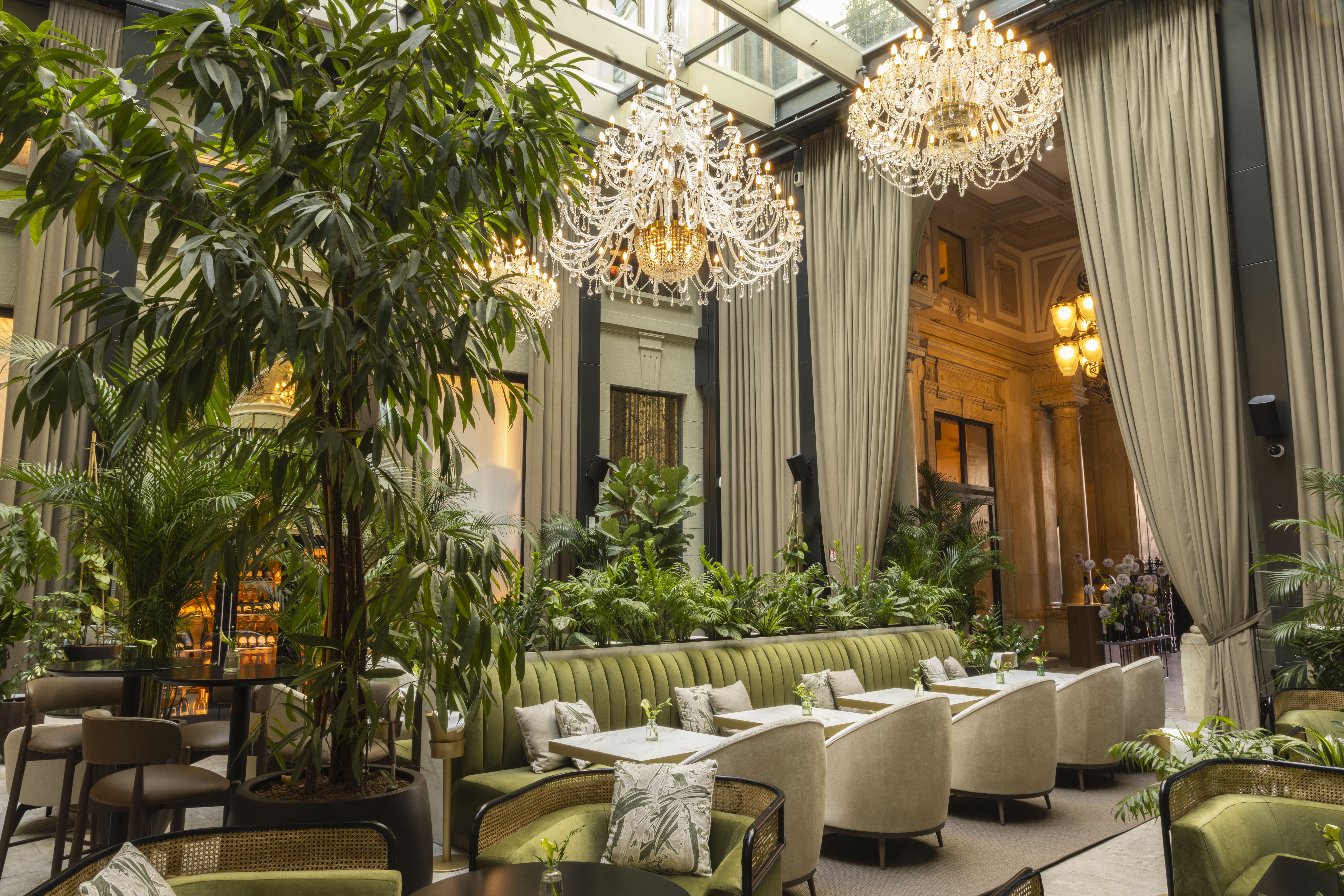 Chic restaurant atrium with lush plants, sparkling chandeliers, and stylish seating.