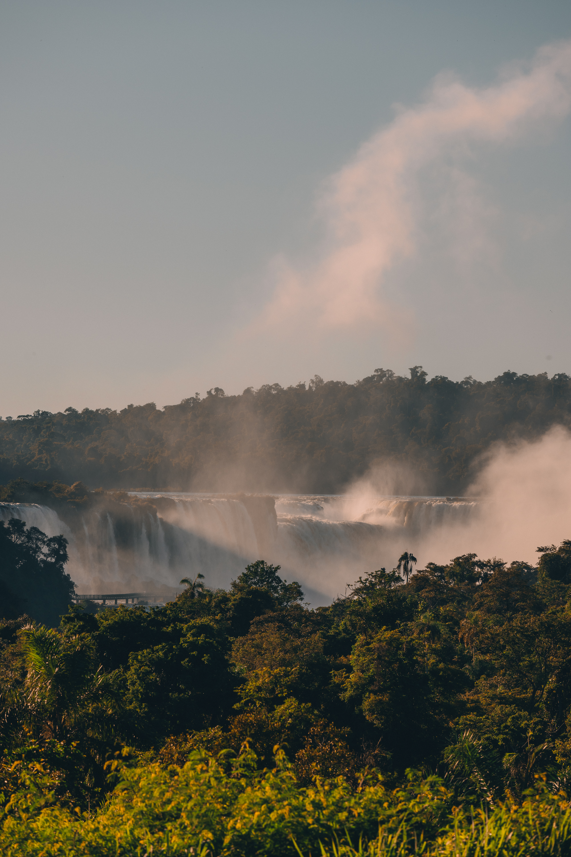 Cascading waterfalls, mist rising over lush tropical forest.