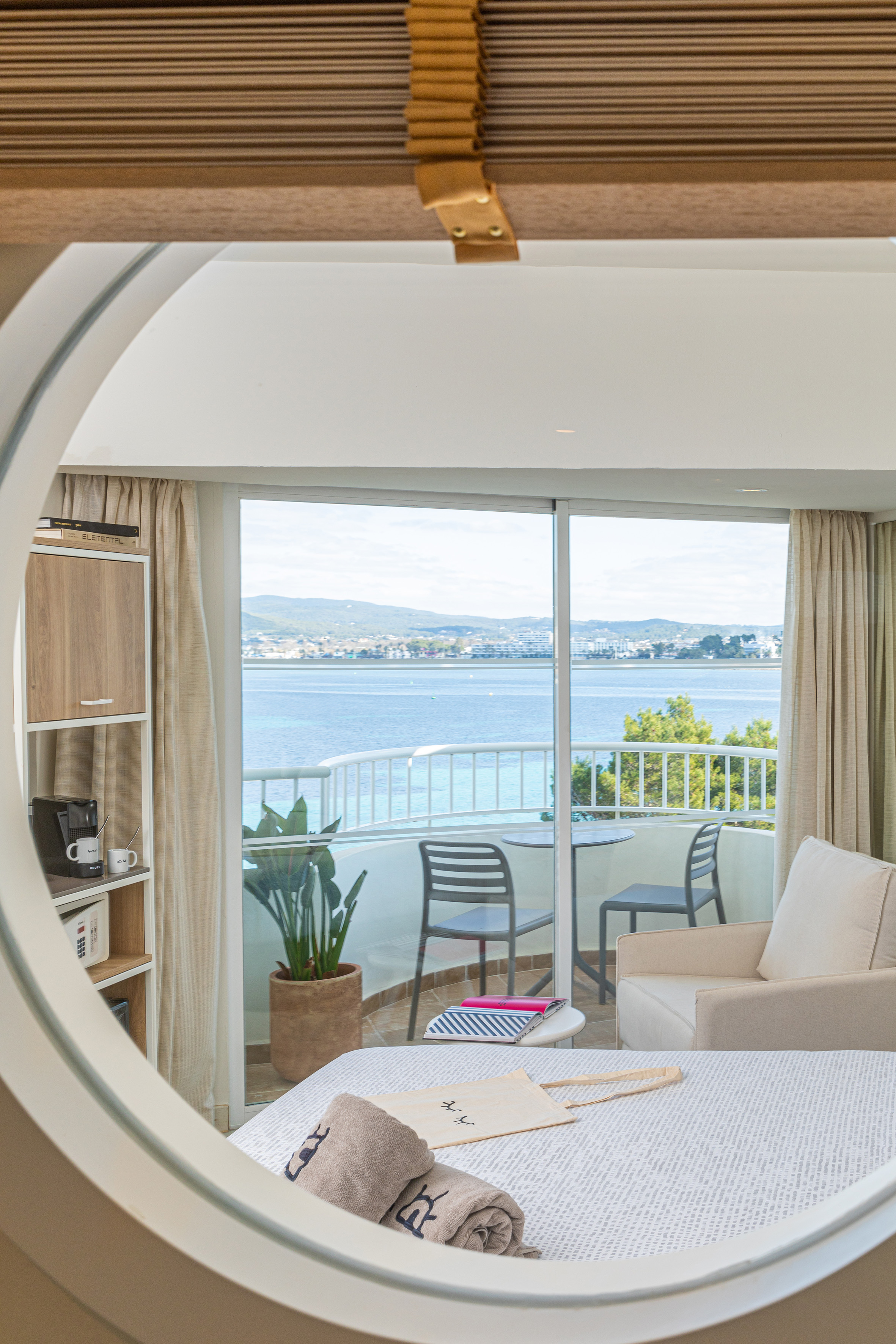 Modern hotel bedroom with sea view balcony, coffee machine, and clean design.