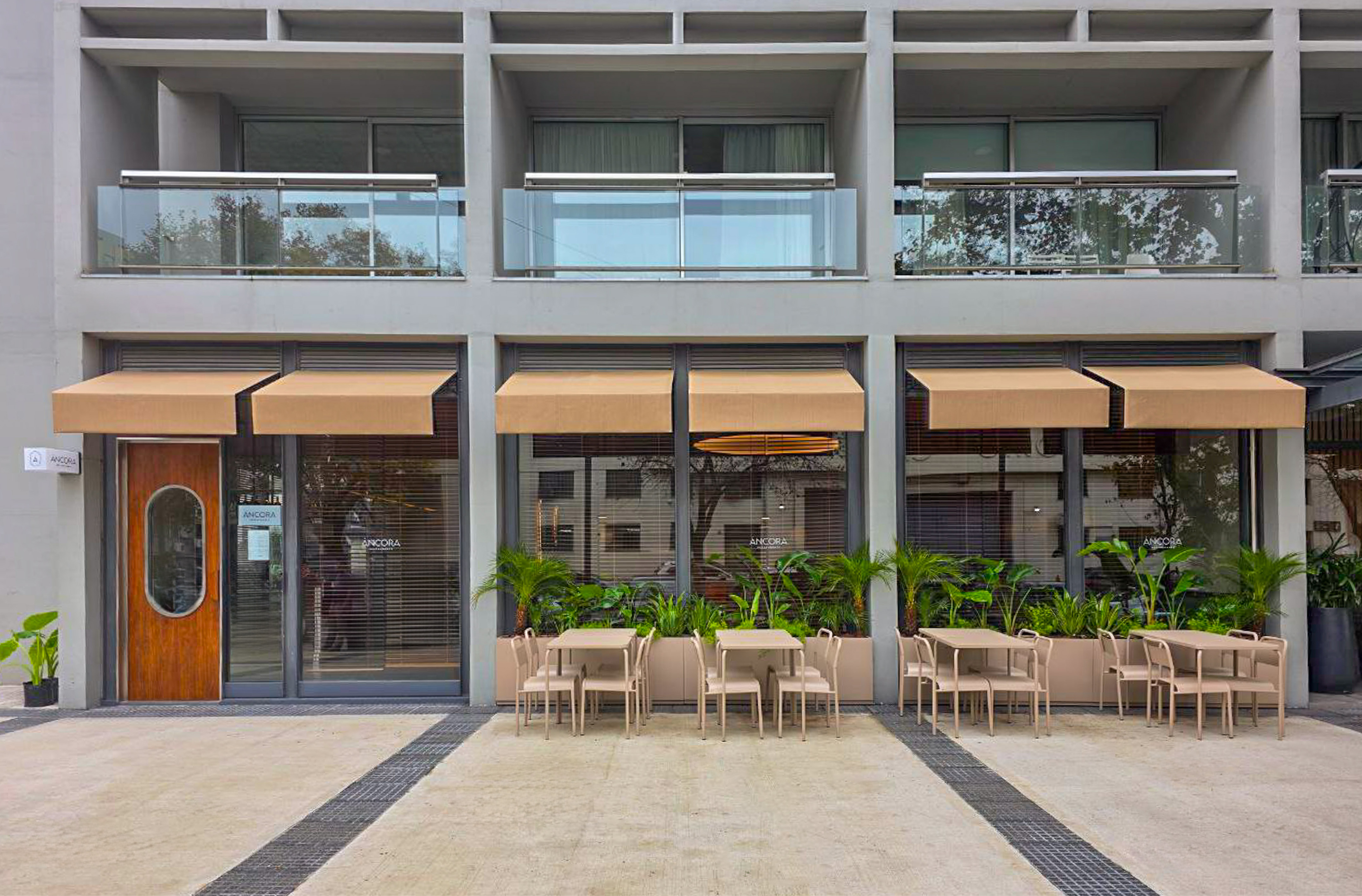 Ancora building facade with outdoor dining, beige awnings, and glass balconies.