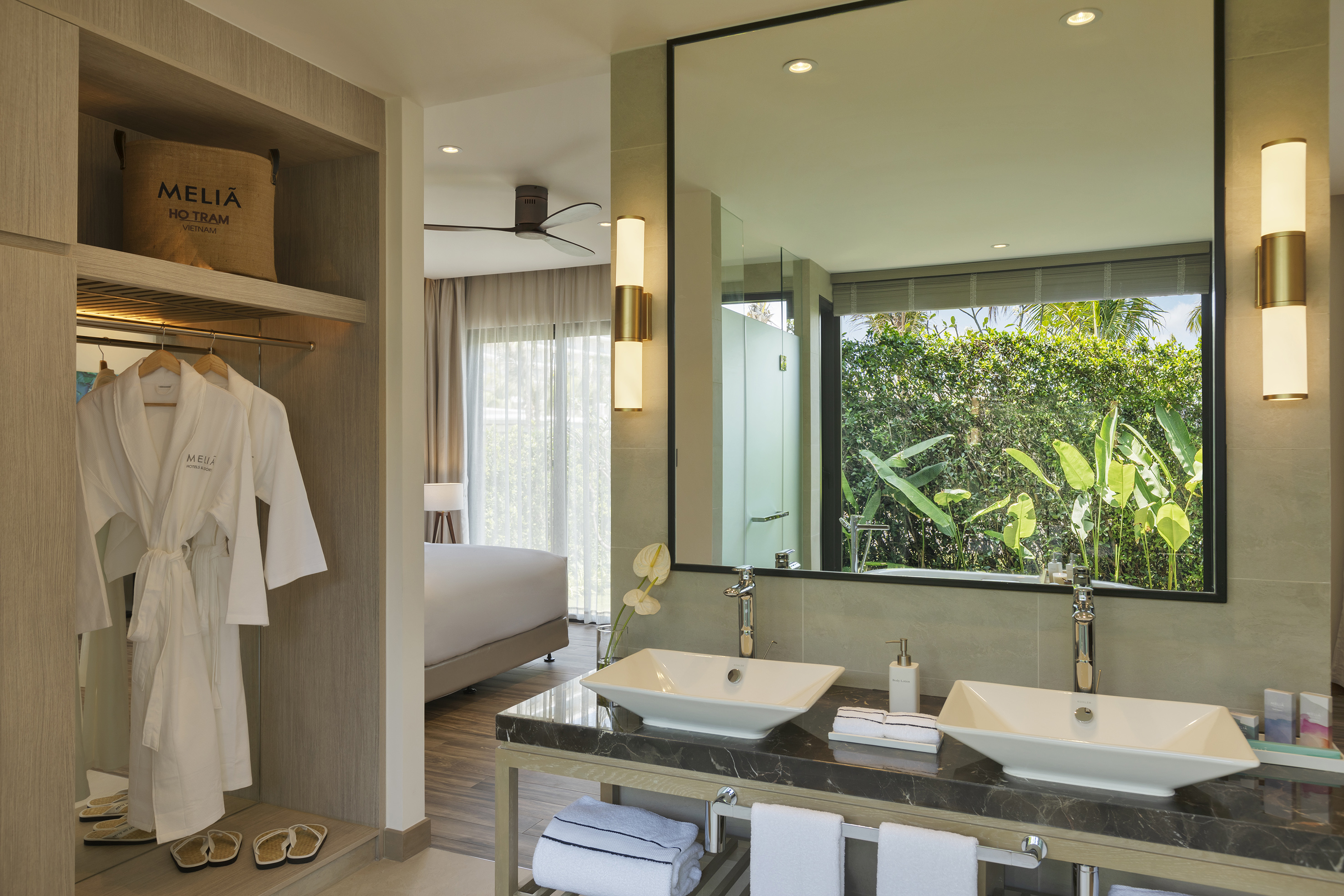 Melia Ho Tram resort bathroom with double vanity, mirror reflecting lush garden.