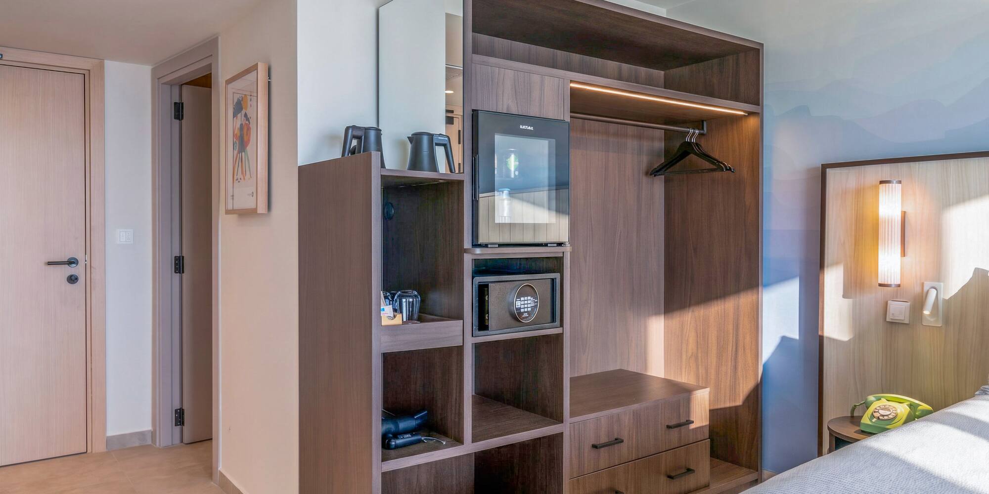 Modern hotel room with built-in dark wood wardrobe, mini-fridge, and safe. - The INNSiDE Room مع تراس - INNSiDE Bugibba, بوجيبا