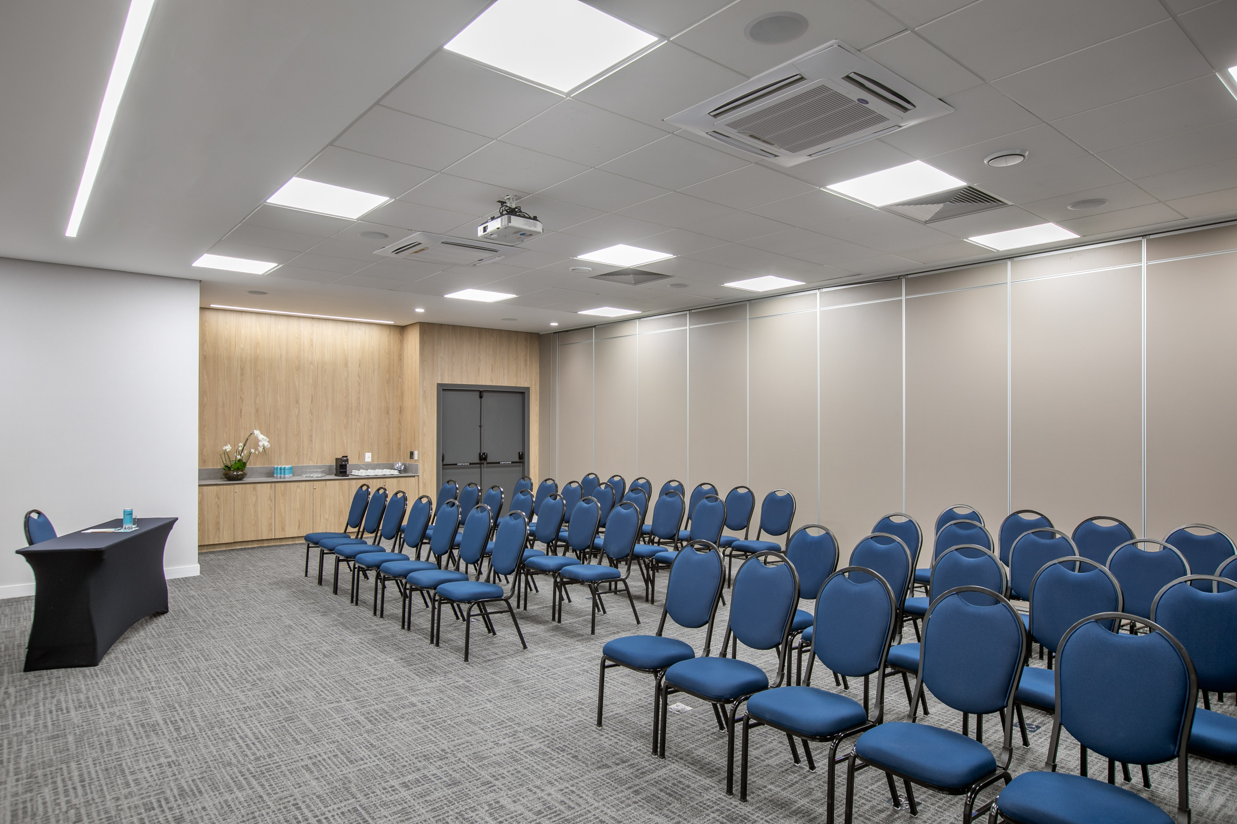 Modern conference room with blue chairs, projector, and presentation table.