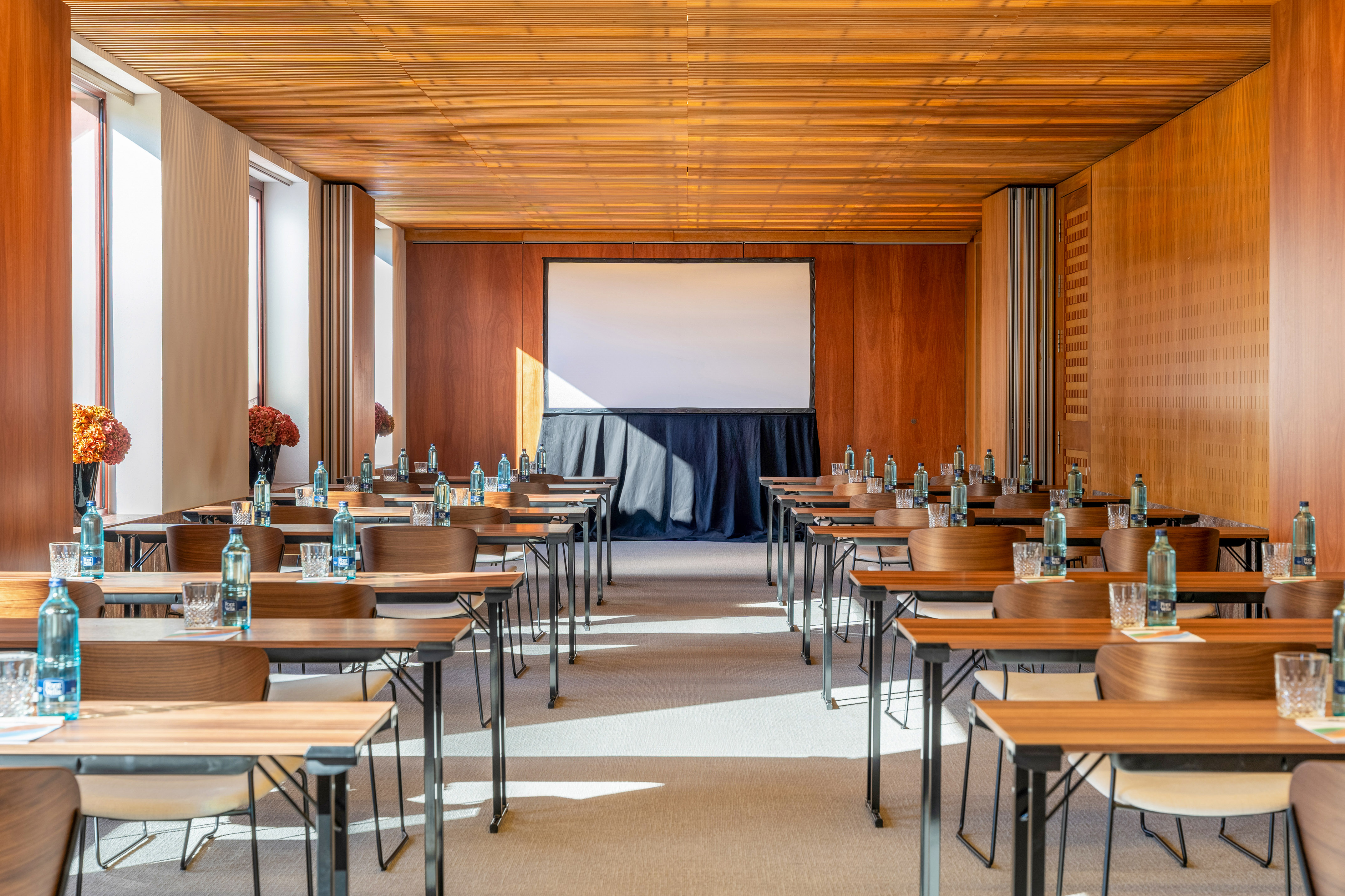 Wood-paneled conference room with tables, chairs, and projection screen.