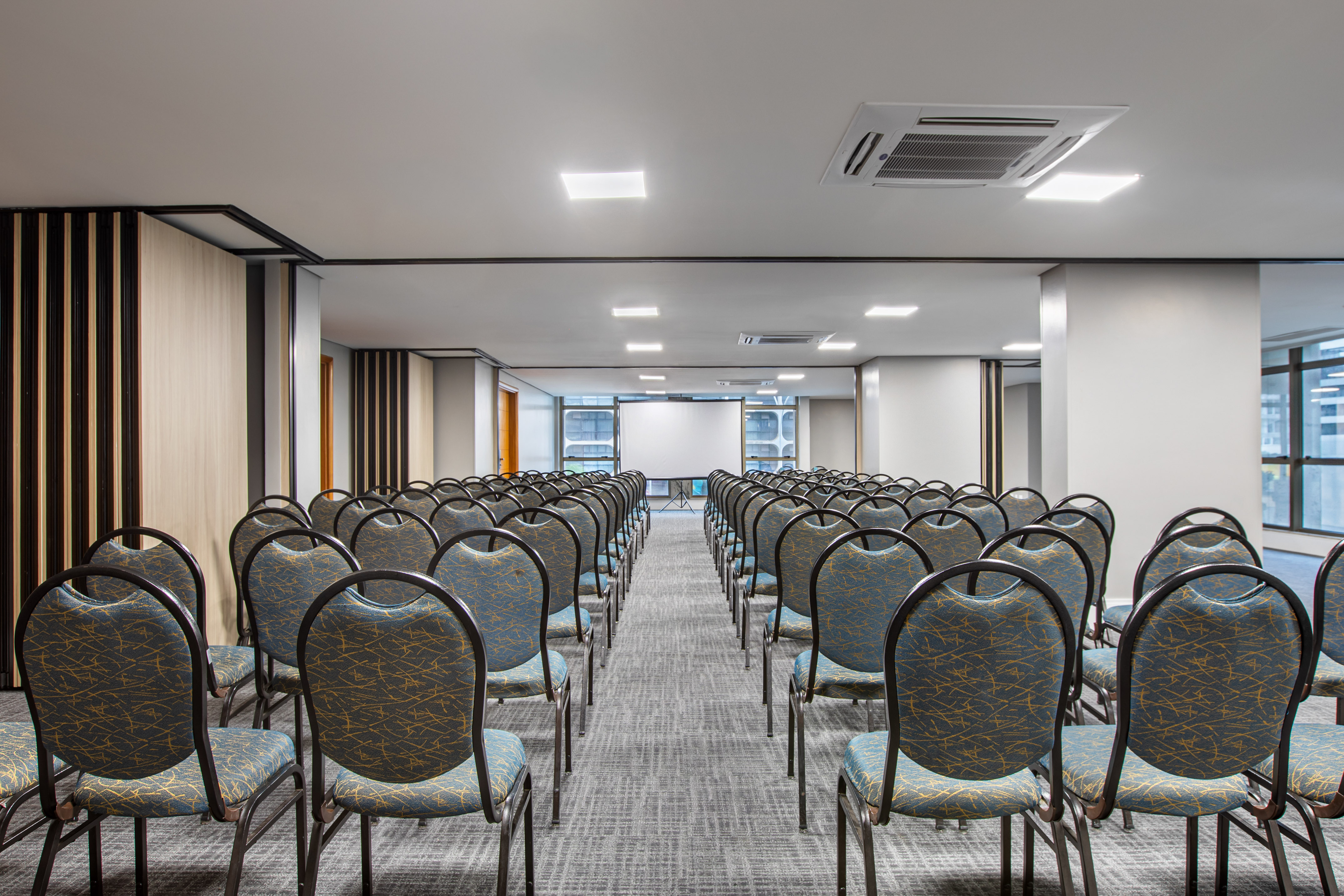 Spacious empty conference room with rows of chairs and a projection screen.