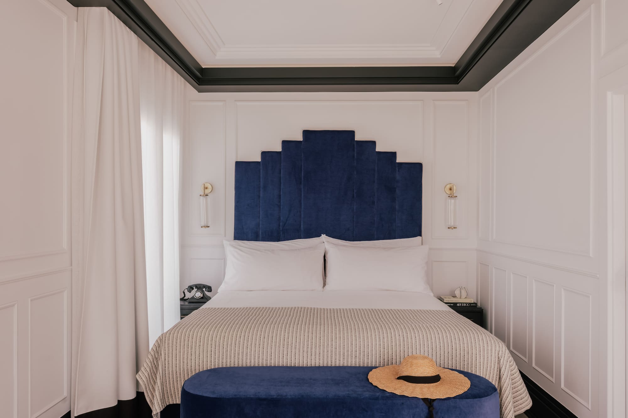 Blue velvet Art Deco headboard in a luxurious hotel bedroom.