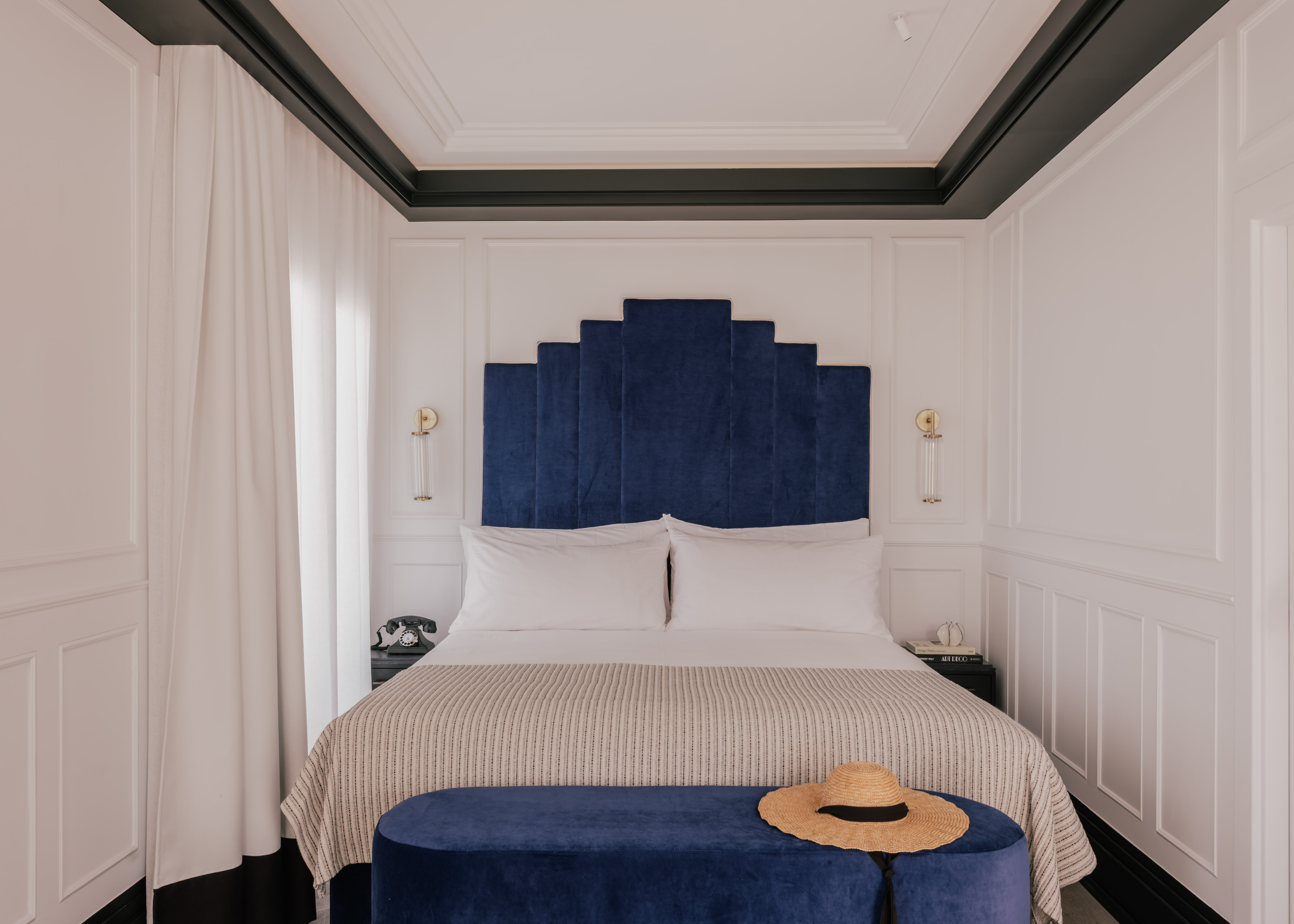 Blue velvet Art Deco headboard in a luxurious hotel bedroom.