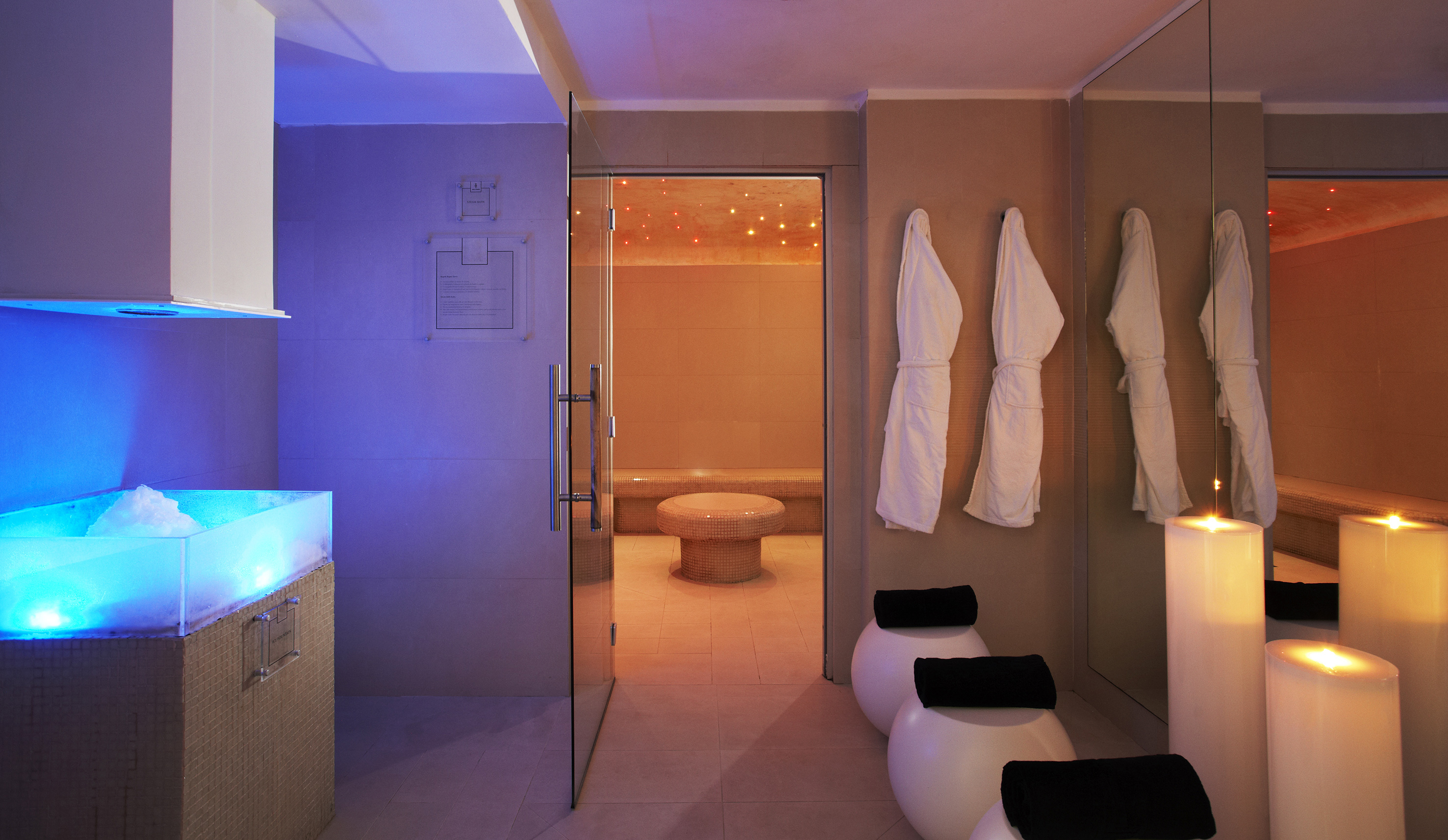 Luxury spa with ice bath, steam room, bathrobes, and glowing candles.