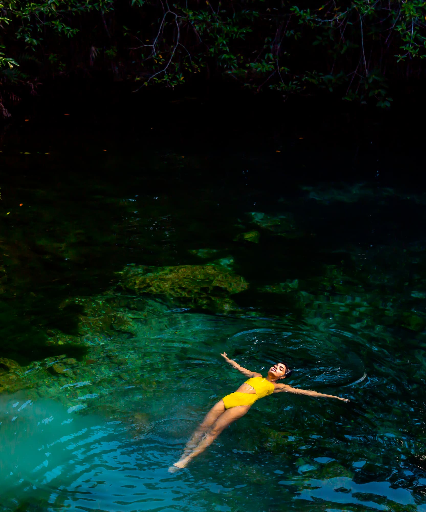 a woman in a yellow swimsuit floating in a body of water