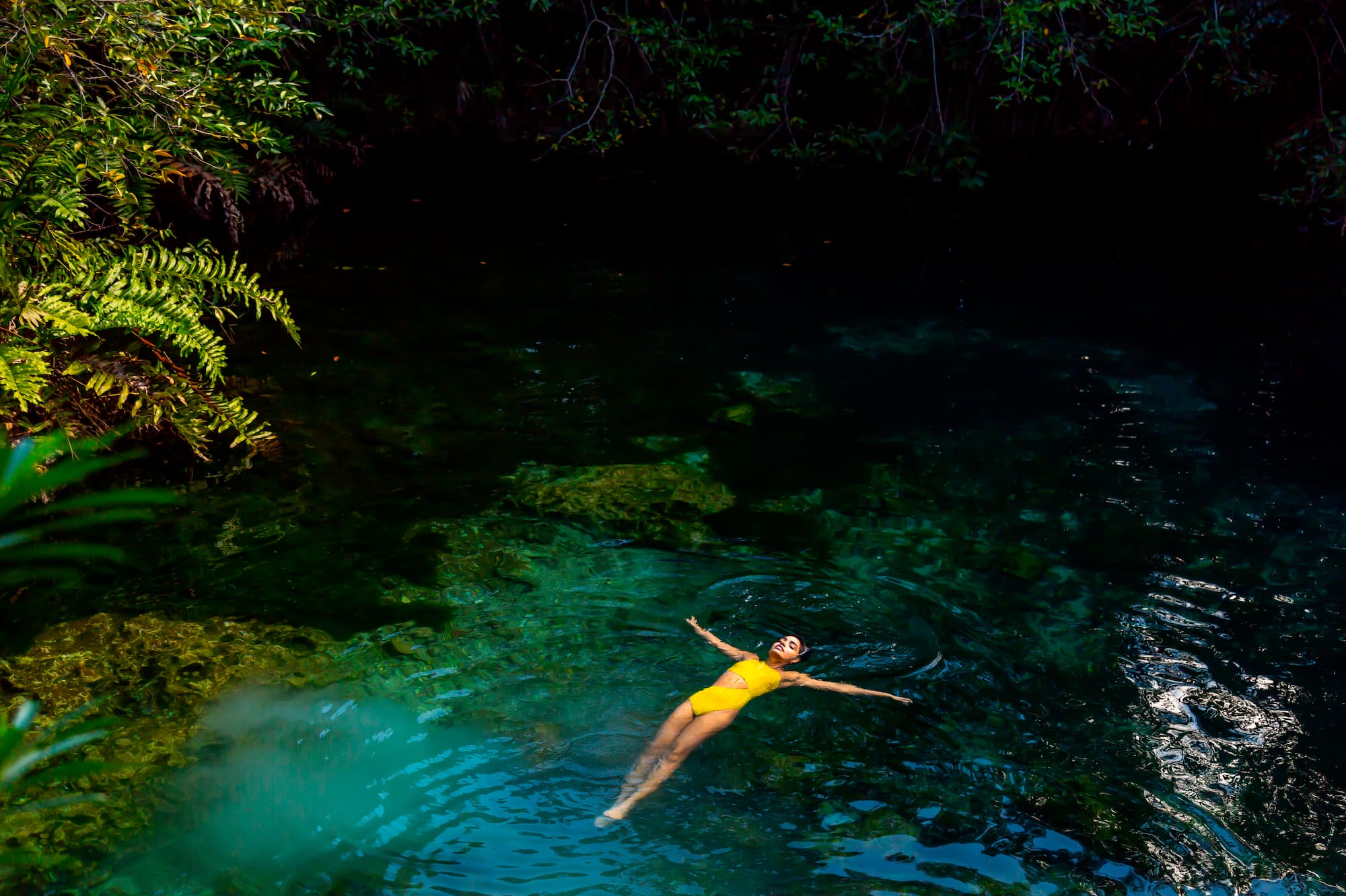 a woman in a yellow swimsuit floating in a body of water