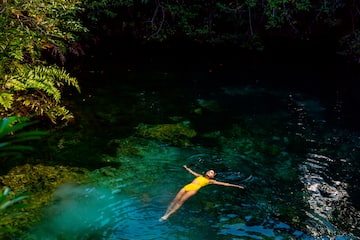 a woman in a yellow swimsuit floating in a body of water
