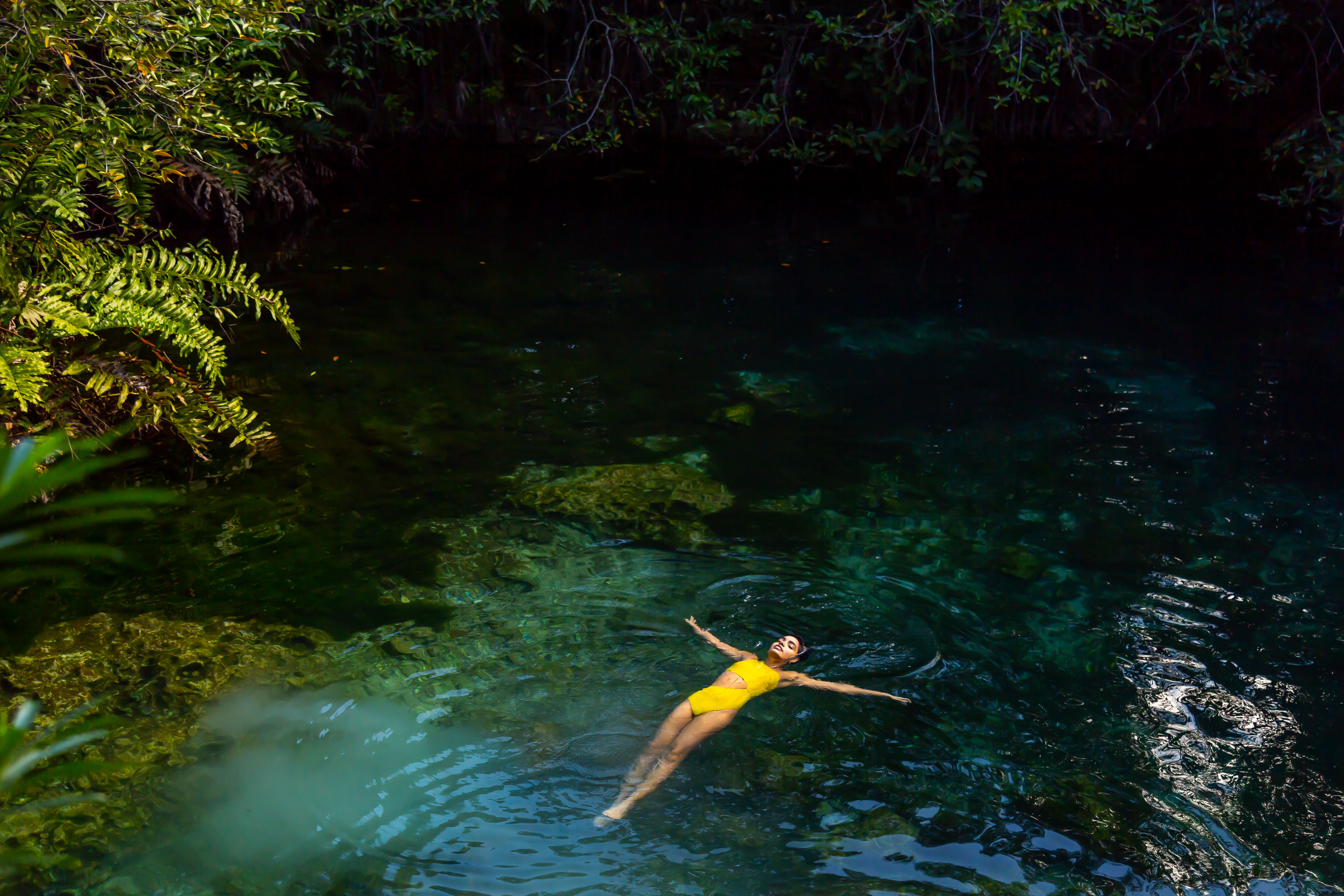 a woman in a yellow swimsuit floating in a body of water