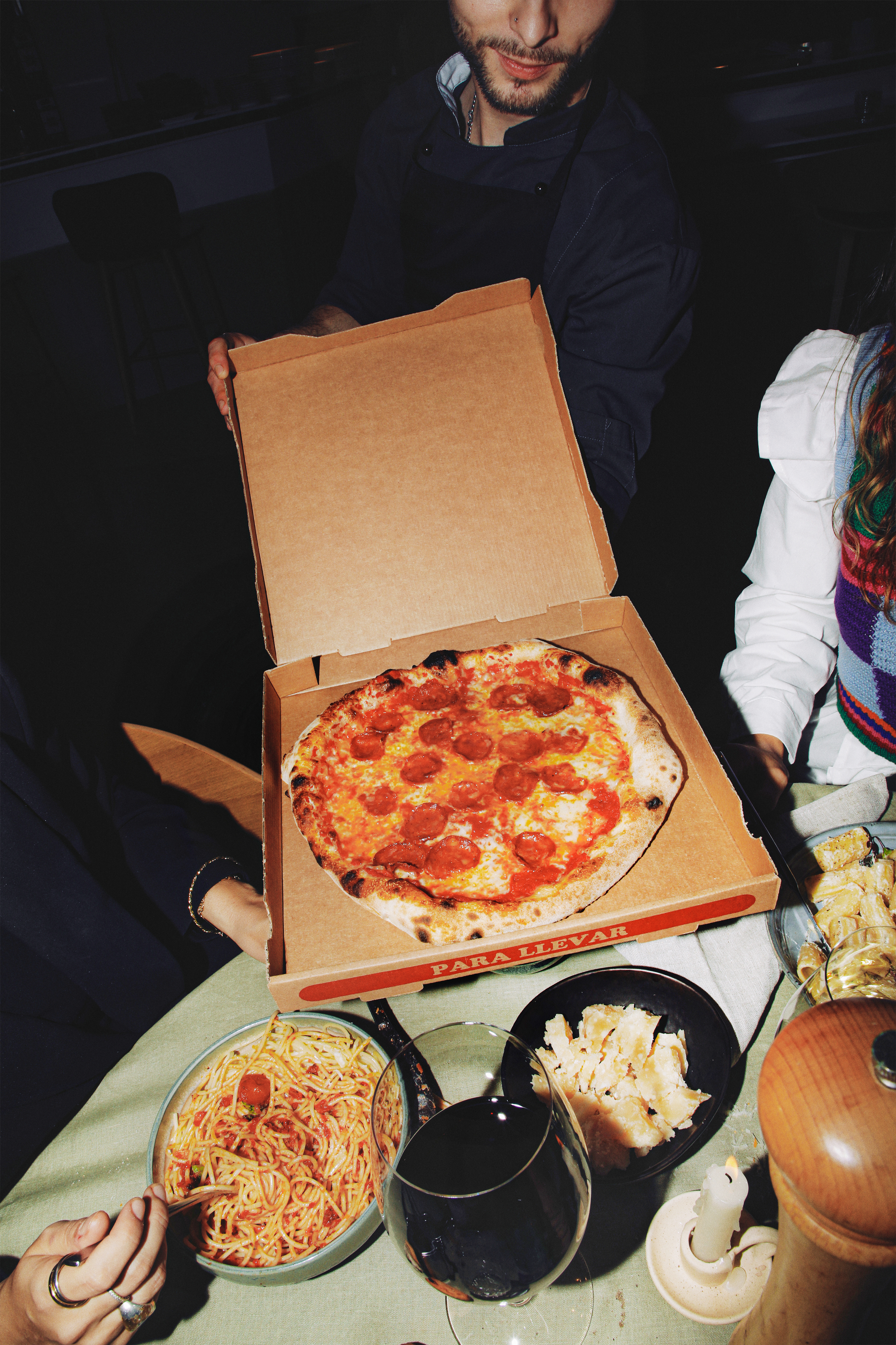 Takeaway pepperoni pizza served with spaghetti, red wine, and cheese for dinner.