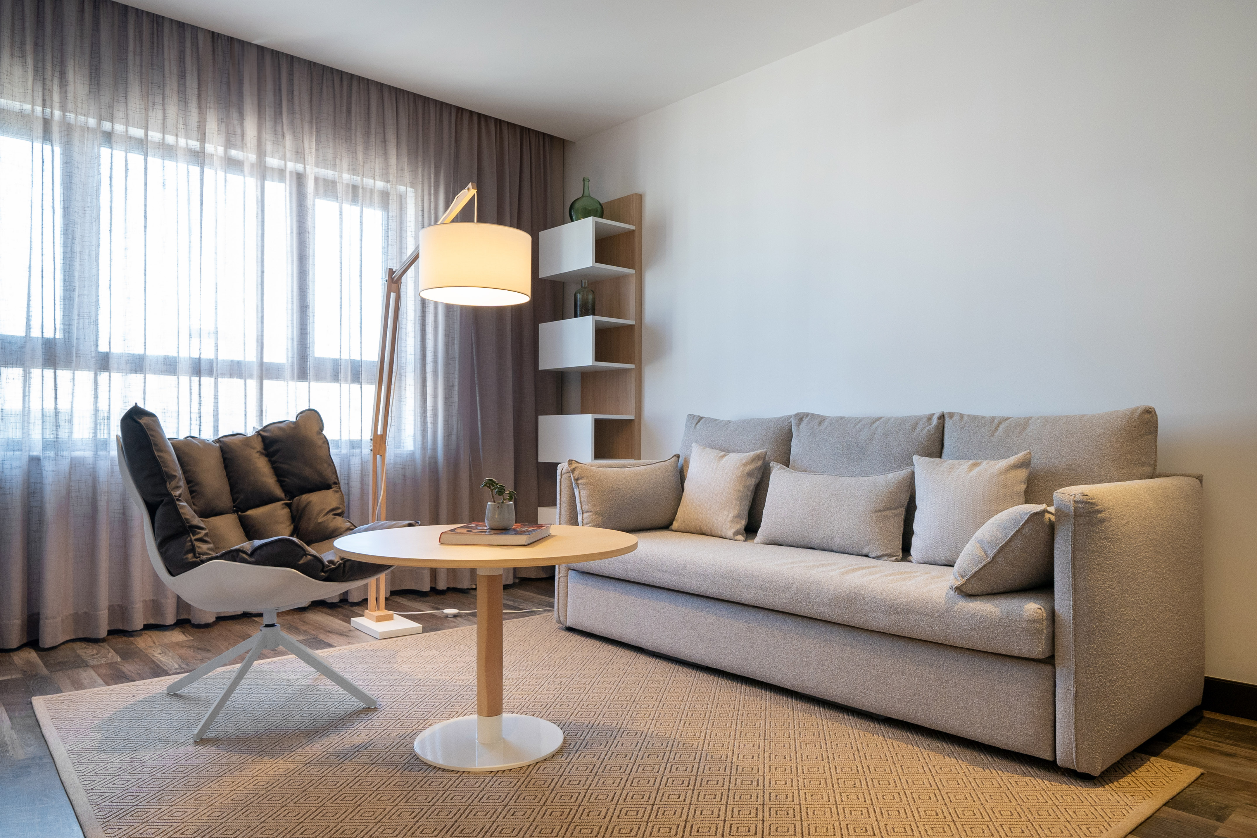 Modern living room with light grey sofa, armchair, coffee table, and floor lamp.