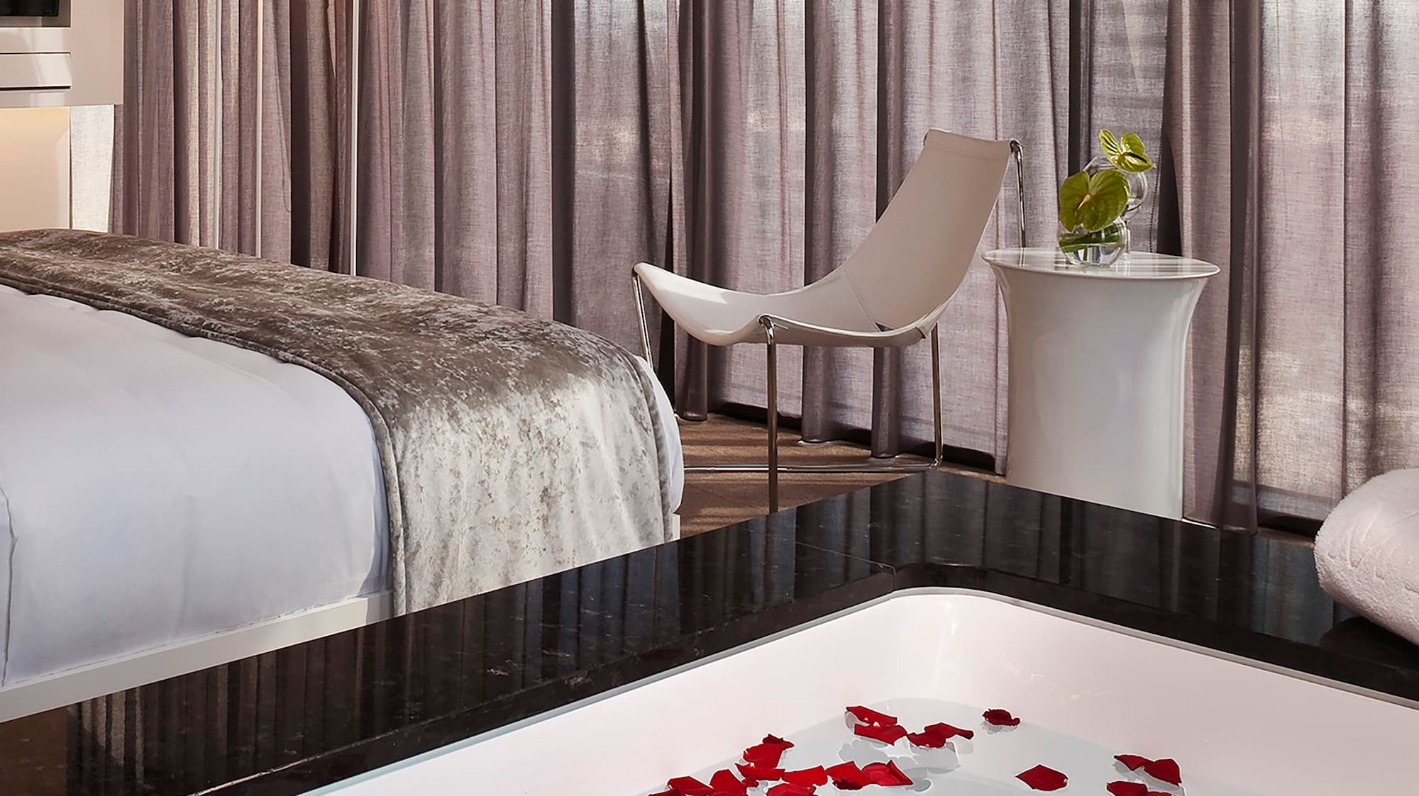 a room with a bed and a bathtub with flowers