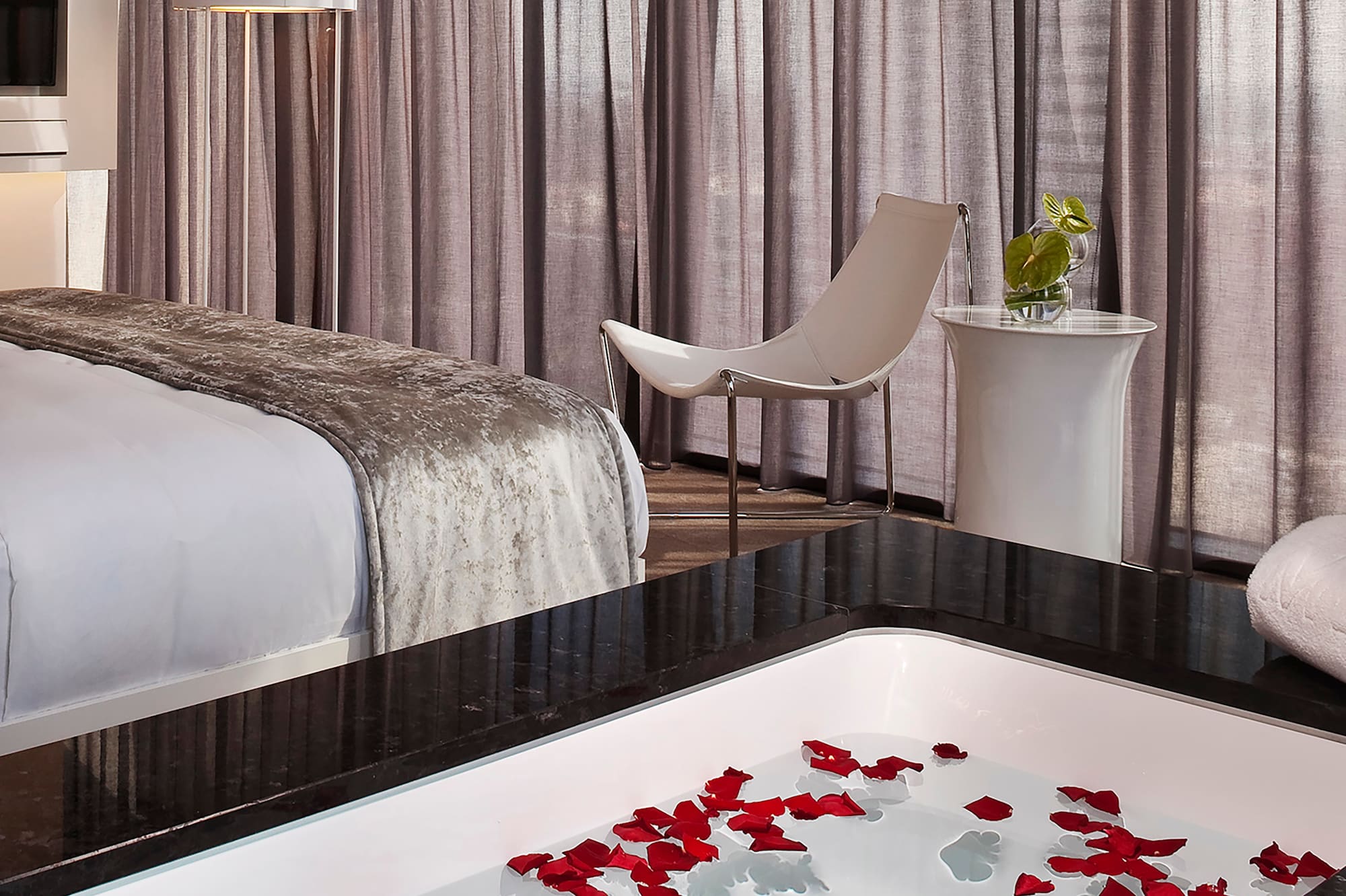 a room with a bed and a bathtub with flowers