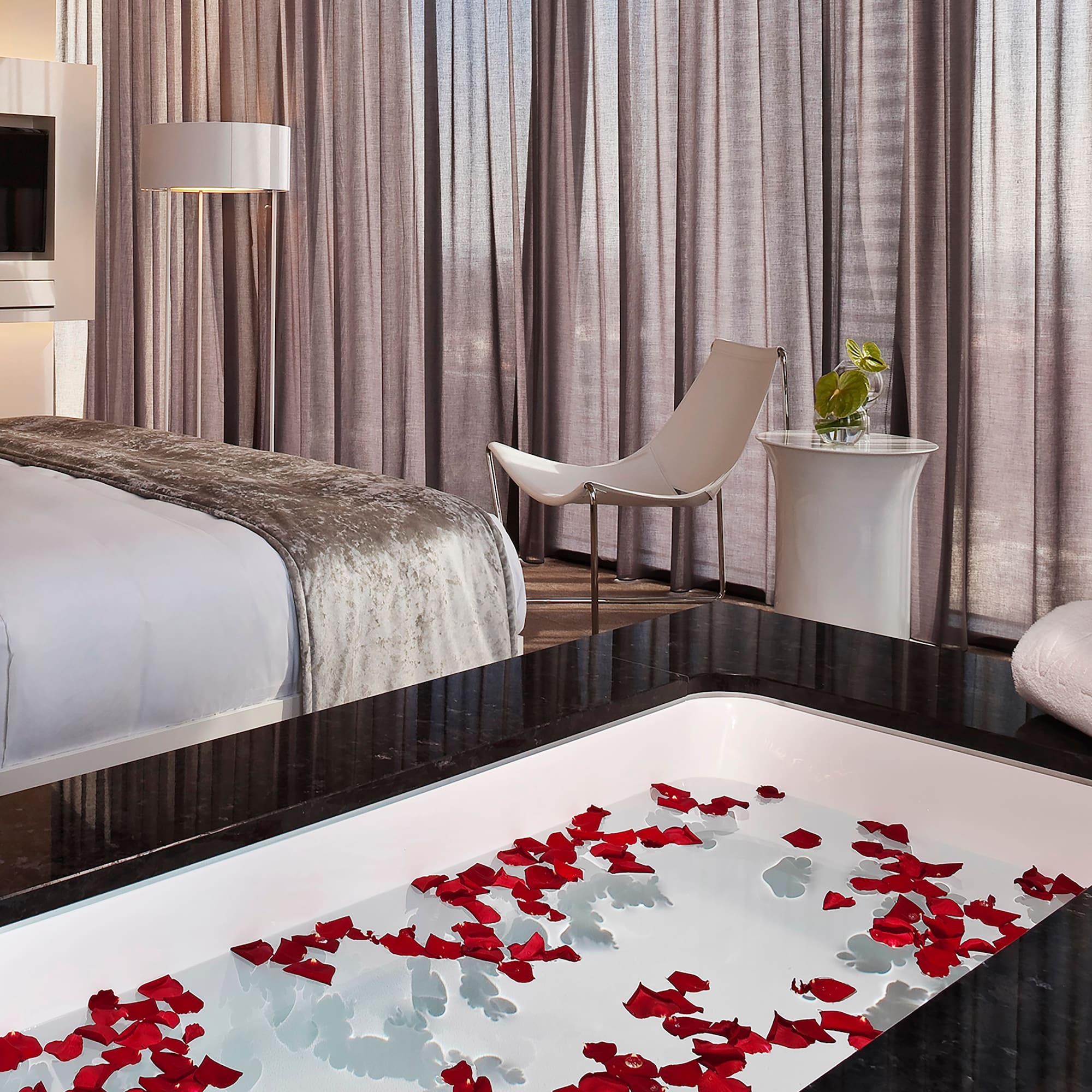 a room with a bed and a bathtub with flowers