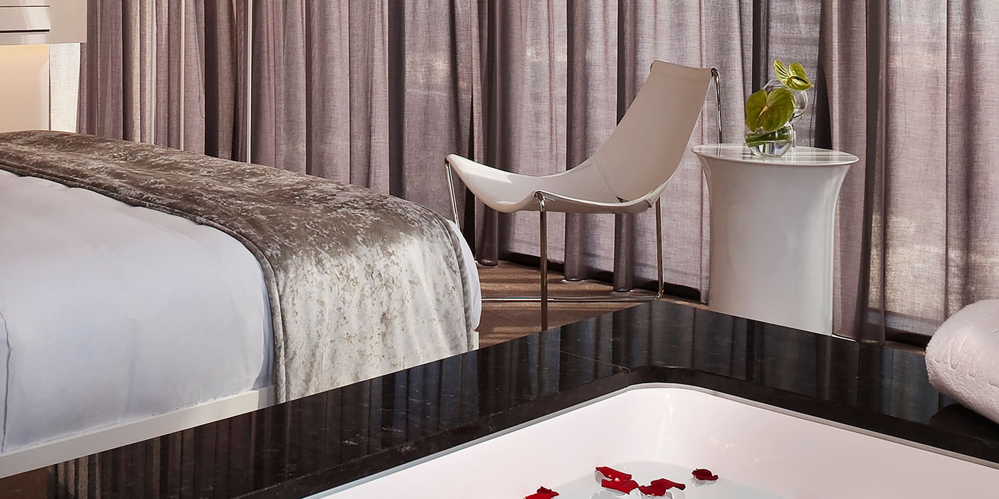 a room with a bed and a bathtub with flowers