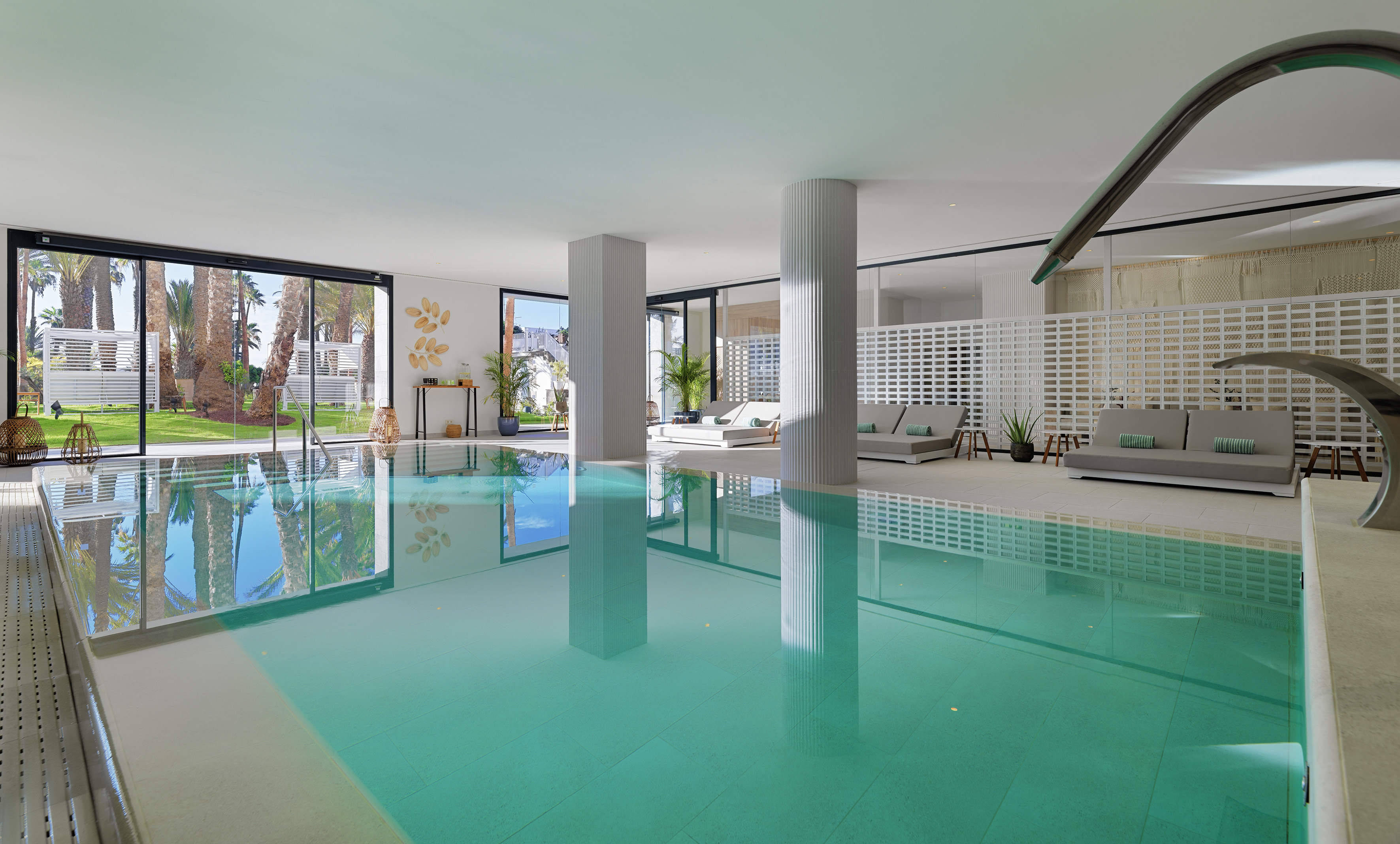 Modern indoor swimming pool at a luxury spa resort with palm tree views.
