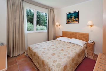 a bed with a headboard and lamps in a room with a window