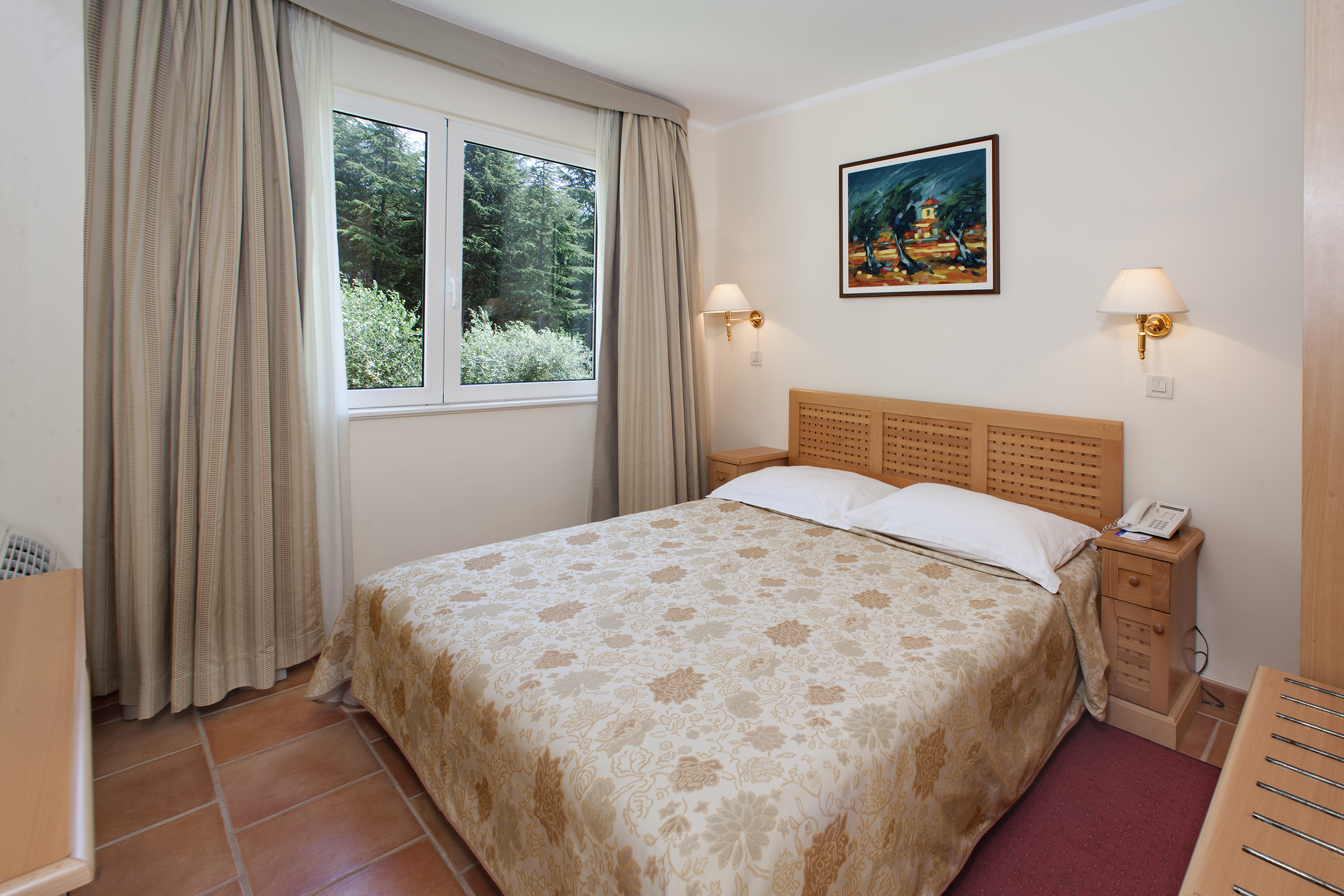 a bed with a headboard and lamps in a room with a window