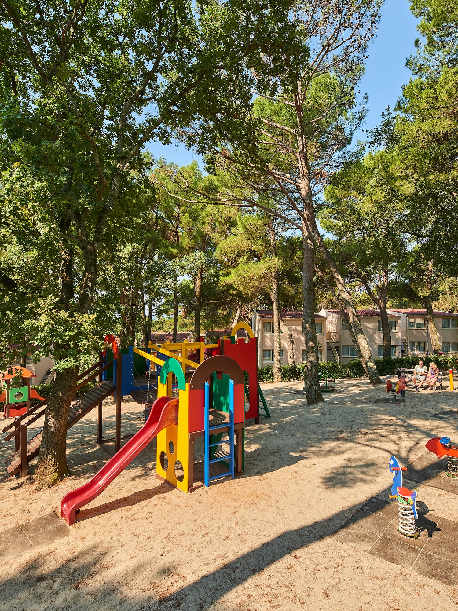 a playground with trees and buildings in the background