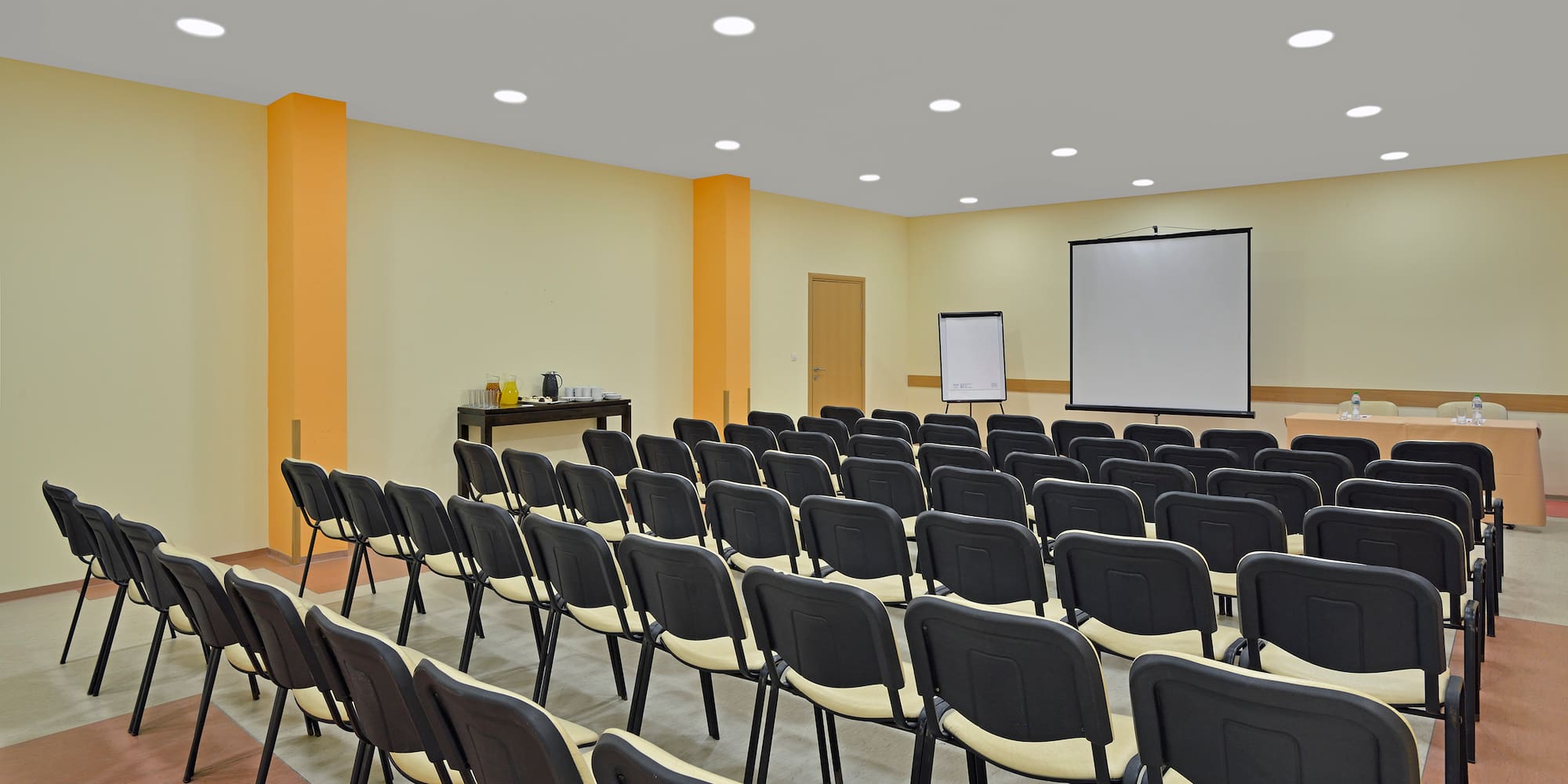 a room with rows of chairs and a projector screen