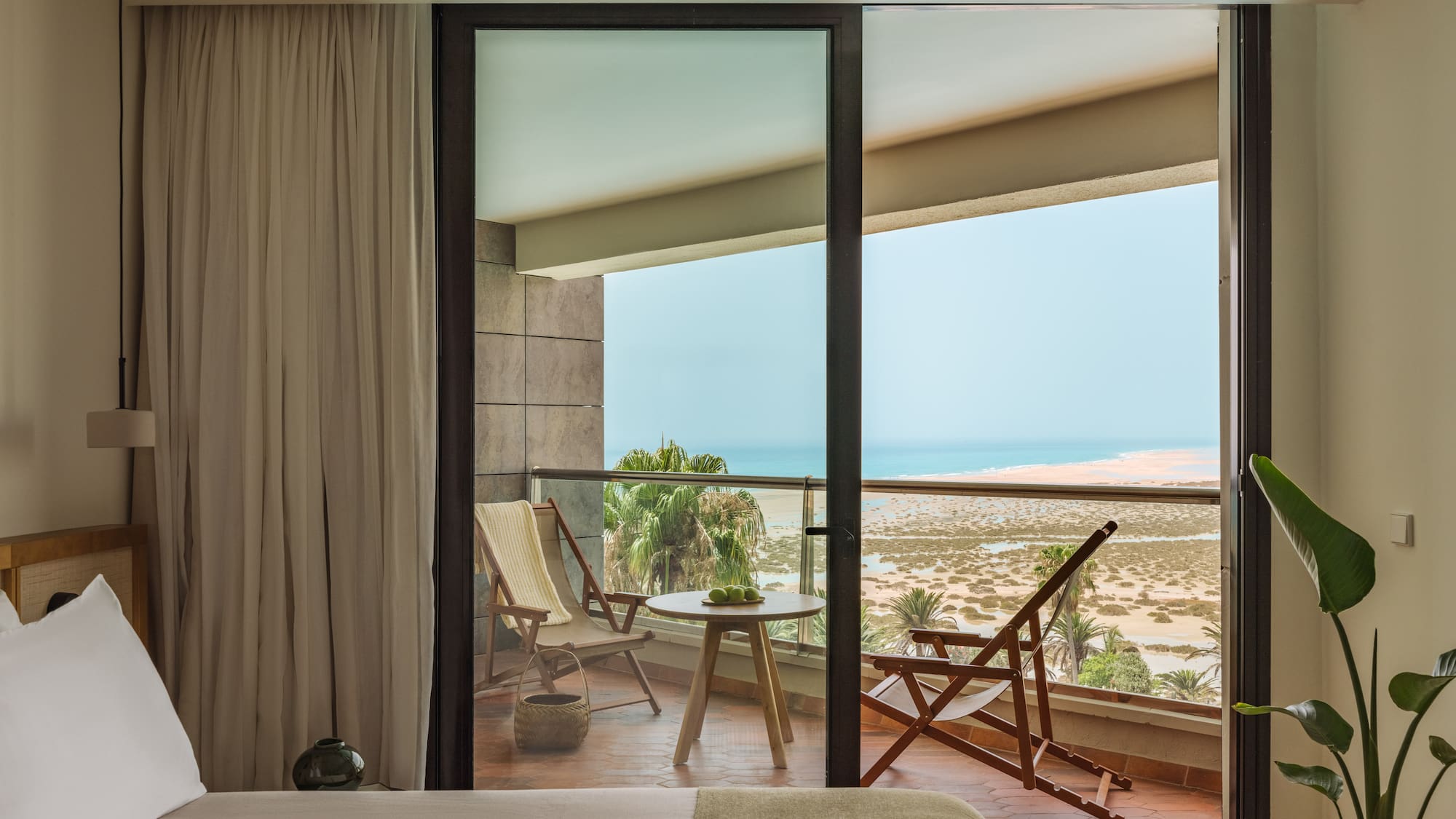 a bedroom with a view of the ocean from the balcony