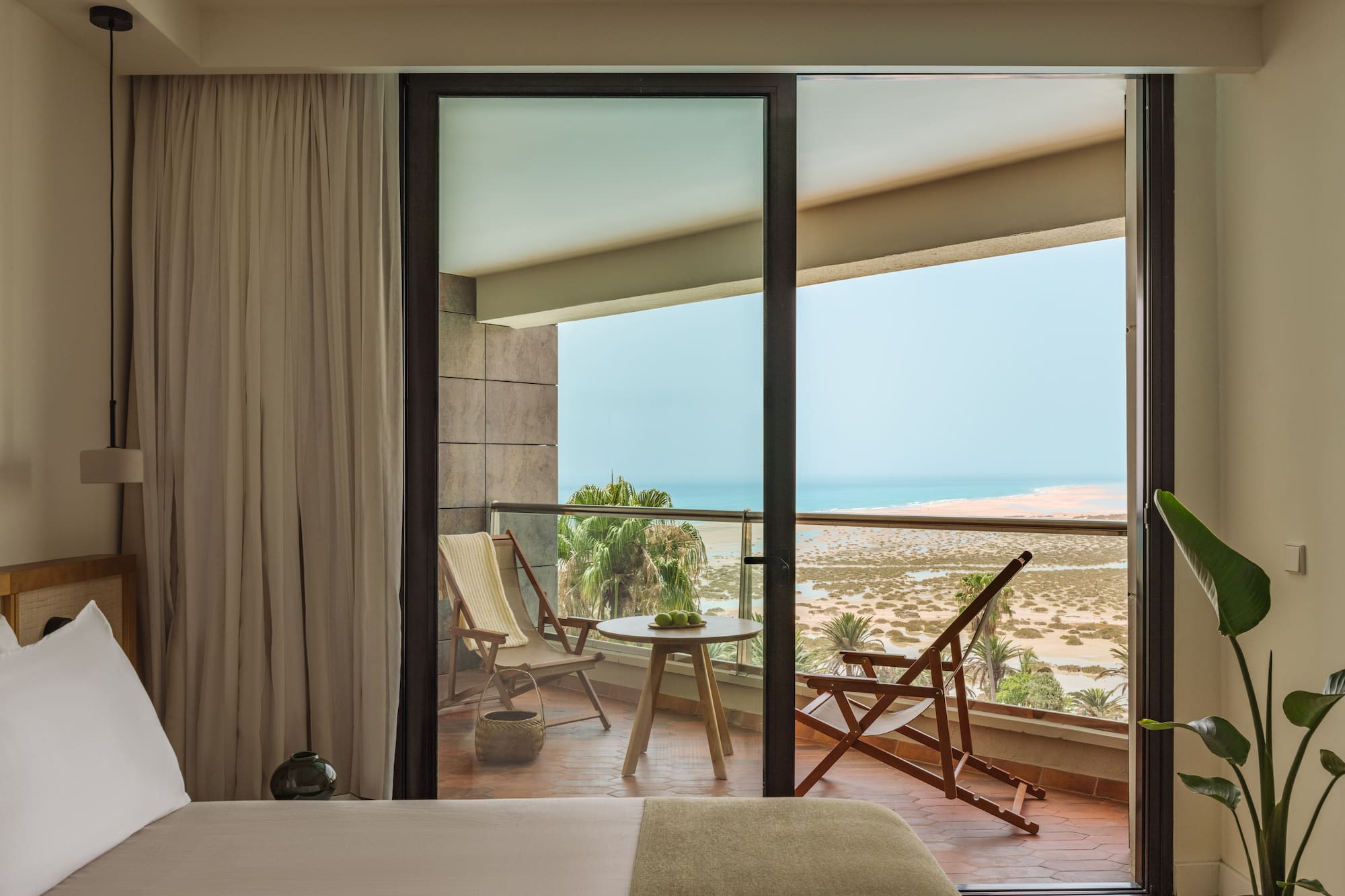 a bedroom with a view of the ocean from the balcony