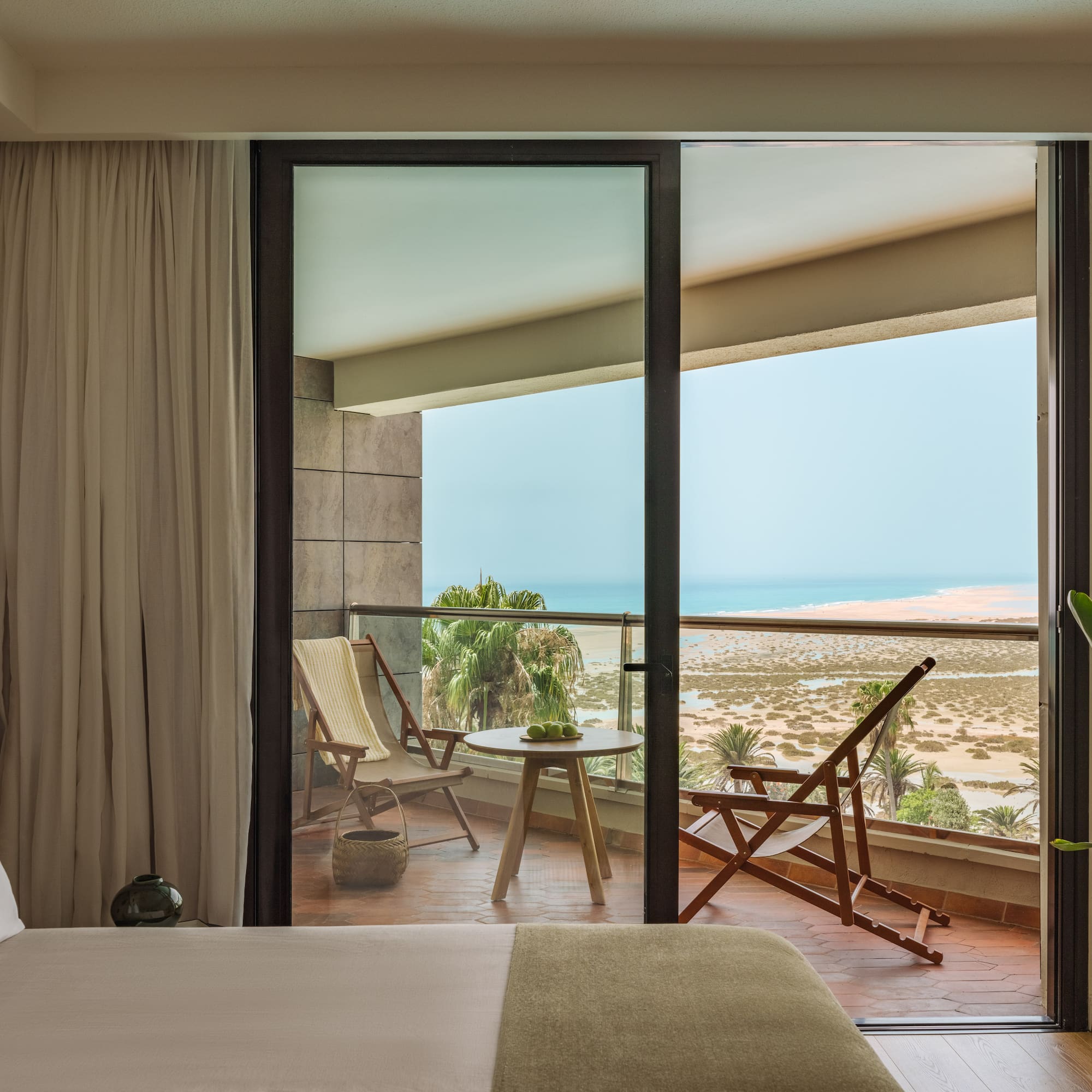a bedroom with a view of the ocean from the balcony