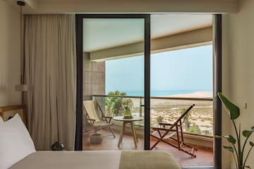 a bedroom with a view of the ocean from the balcony