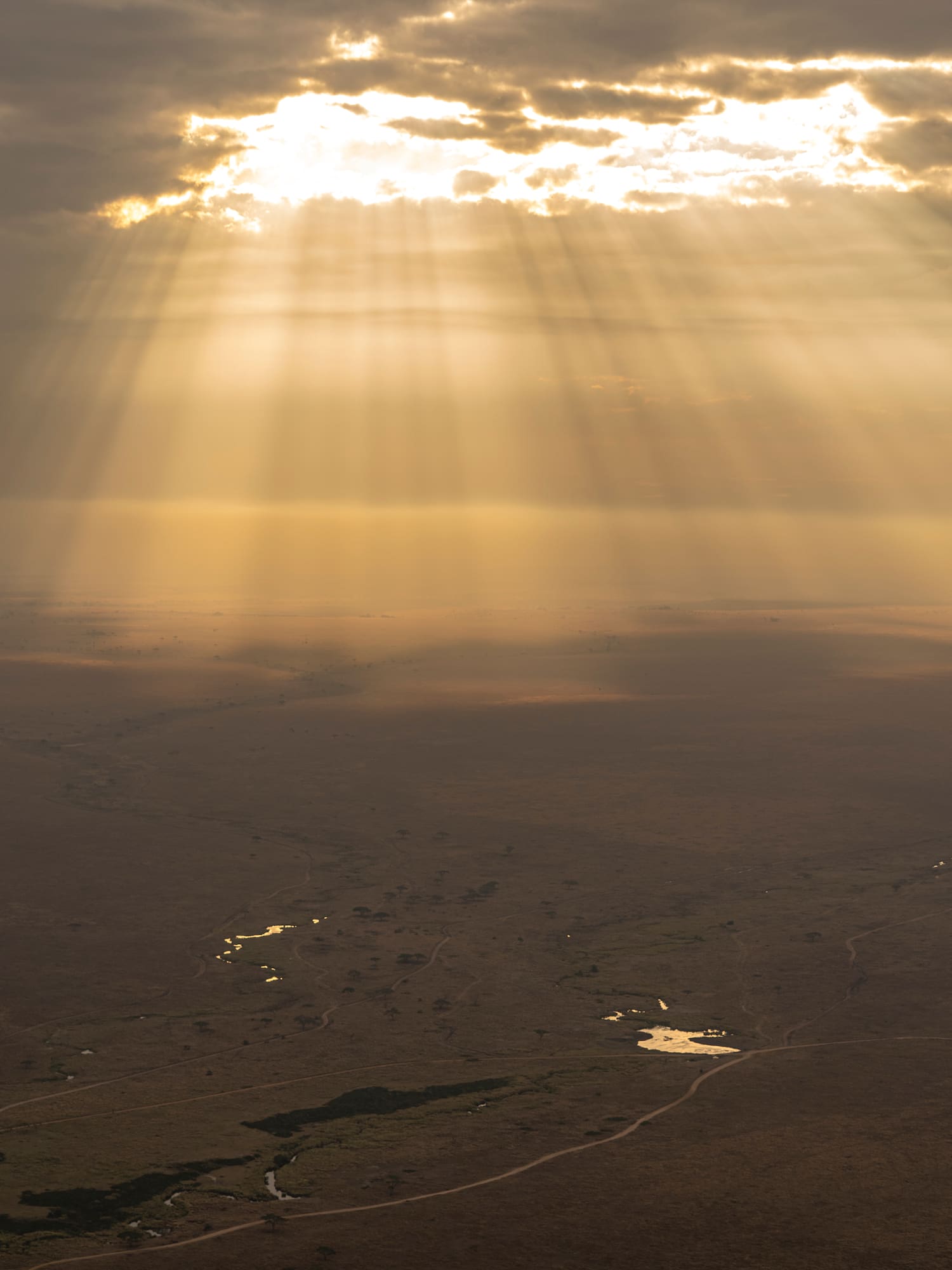 sun shining through clouds over a desert