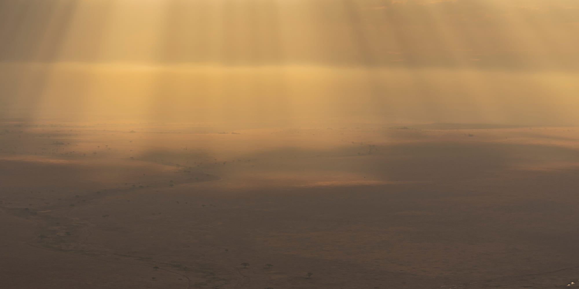 sun shining through clouds over a desert