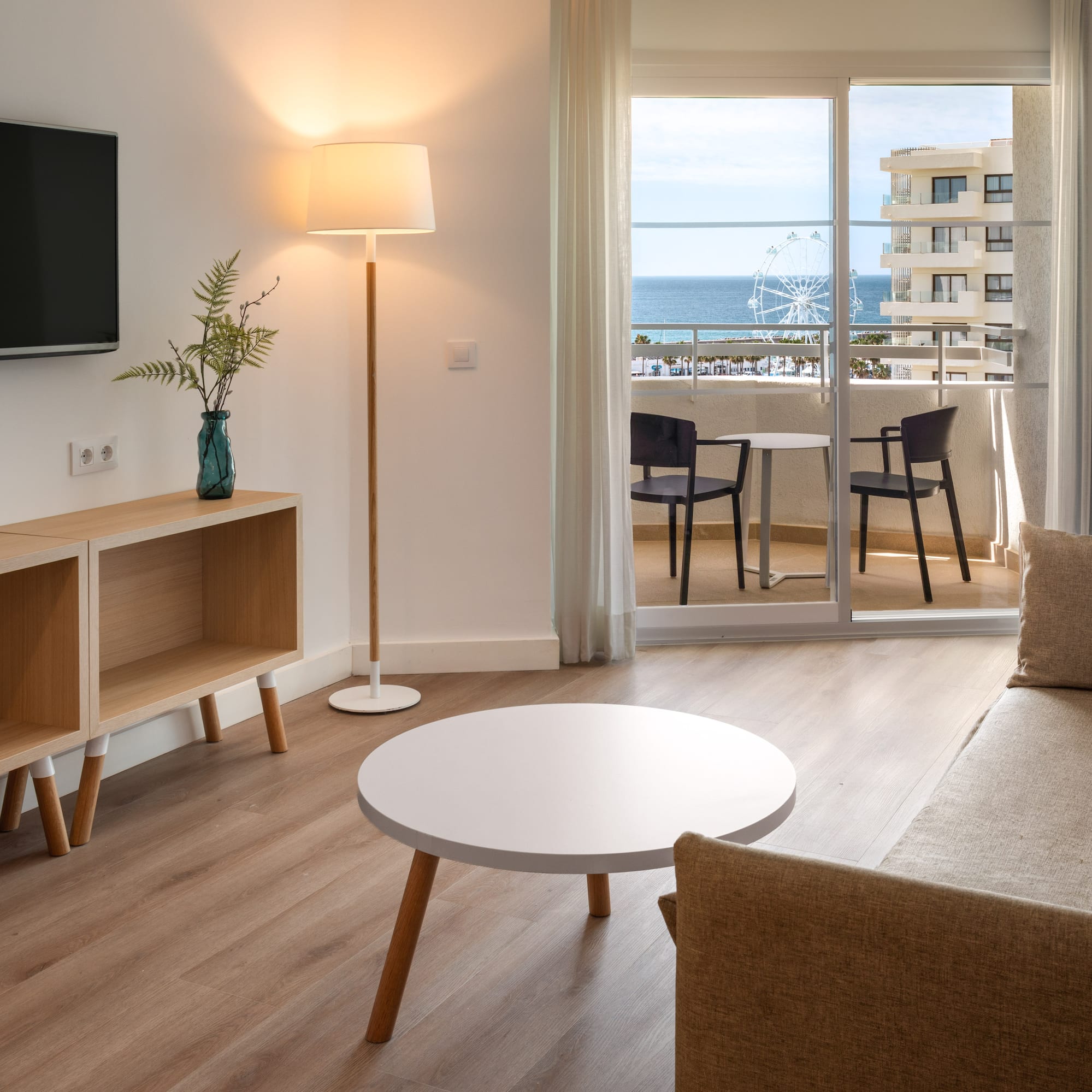 Coastal hotel room living area with balcony, sea view, and modern furnishings.