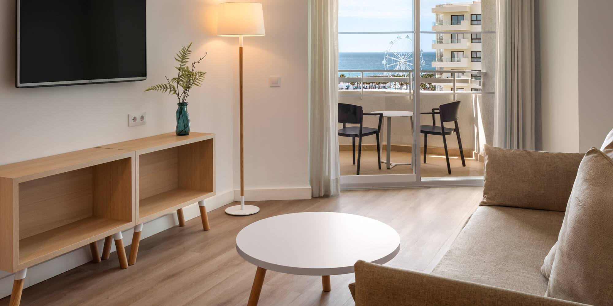 Coastal hotel room living area with balcony, sea view, and modern furnishings.