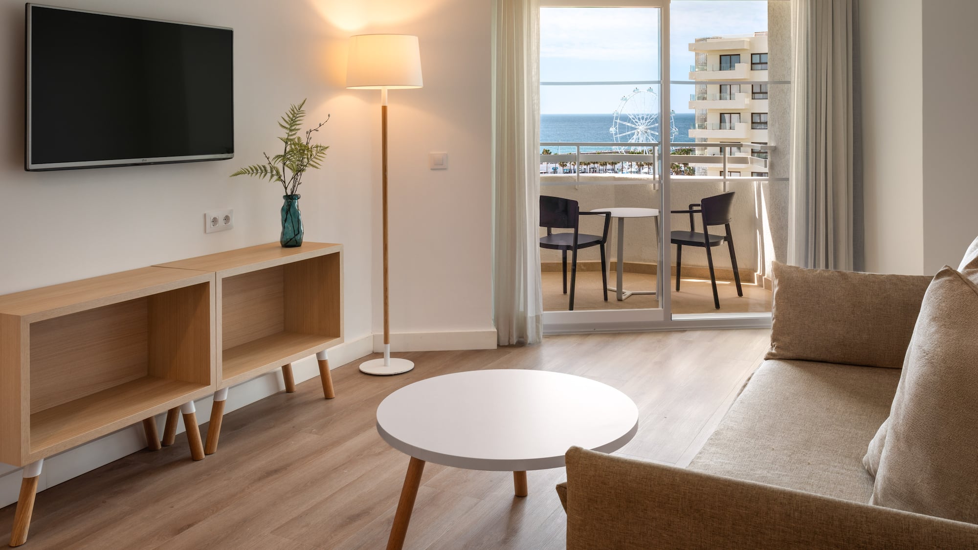 Coastal hotel room living area with balcony, sea view, and modern furnishings.