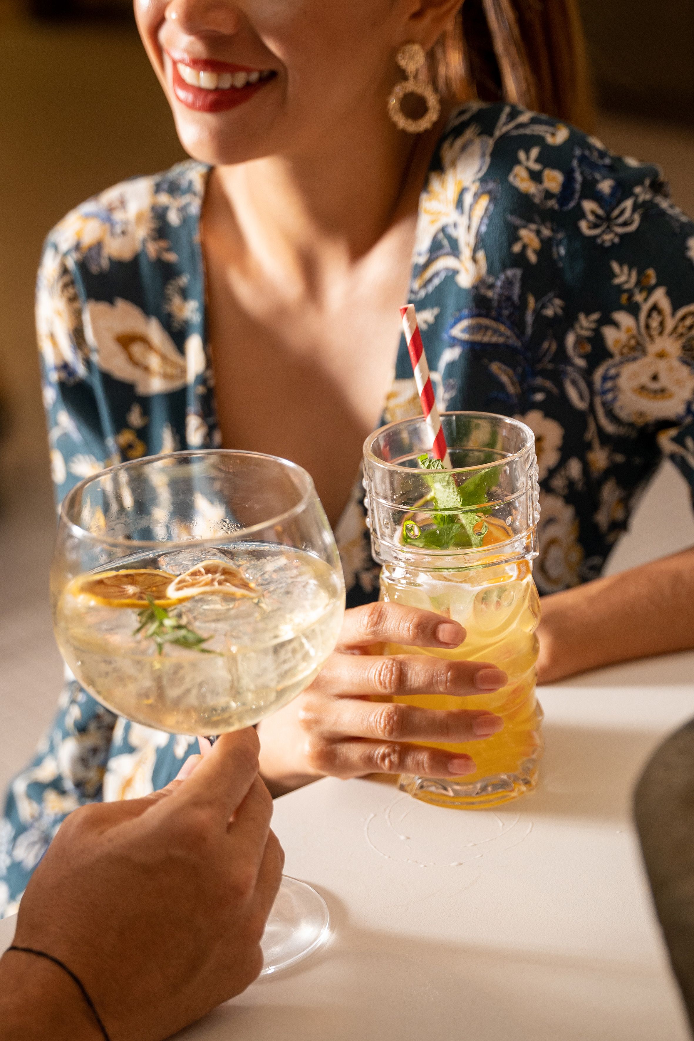 Smiling woman with citrus cocktail, person holding gin and tonic. Refreshing drinks.