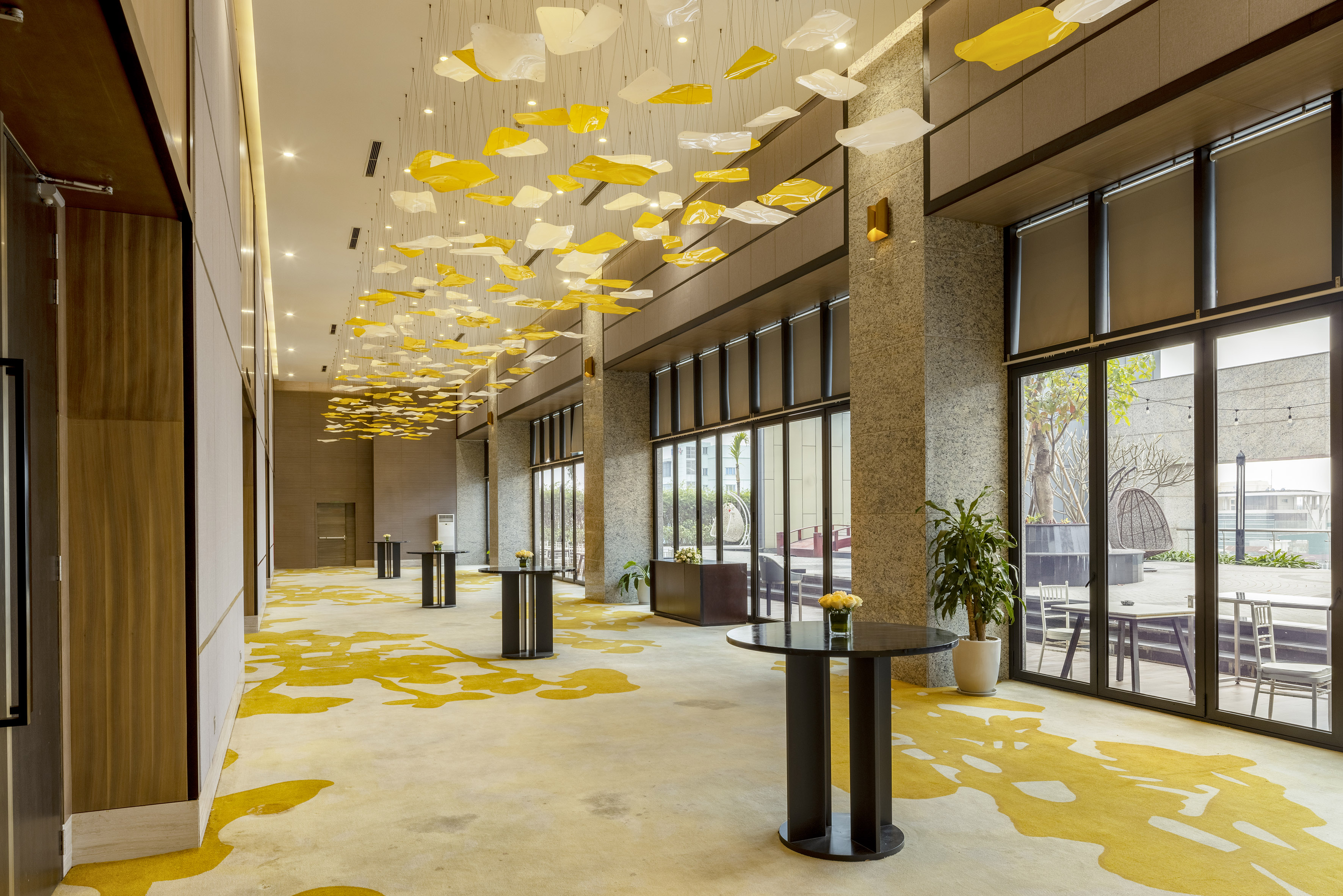 Modern hotel lobby with yellow carpet, unique ceiling lights, and cocktail tables. - Grand Ballroom - Meliá Vinpearl Thanh Hoa, Thanh Hoa