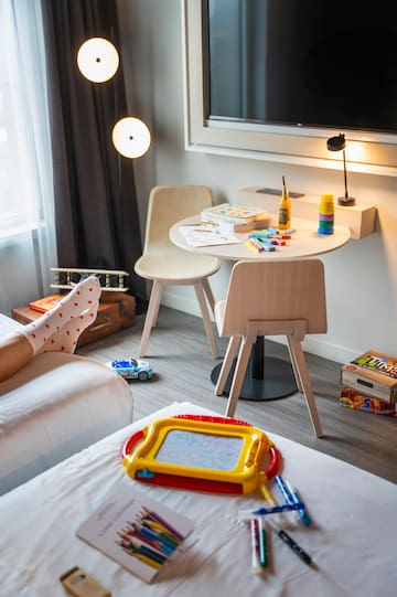 a child's feet on a bed in a room with a table and toys